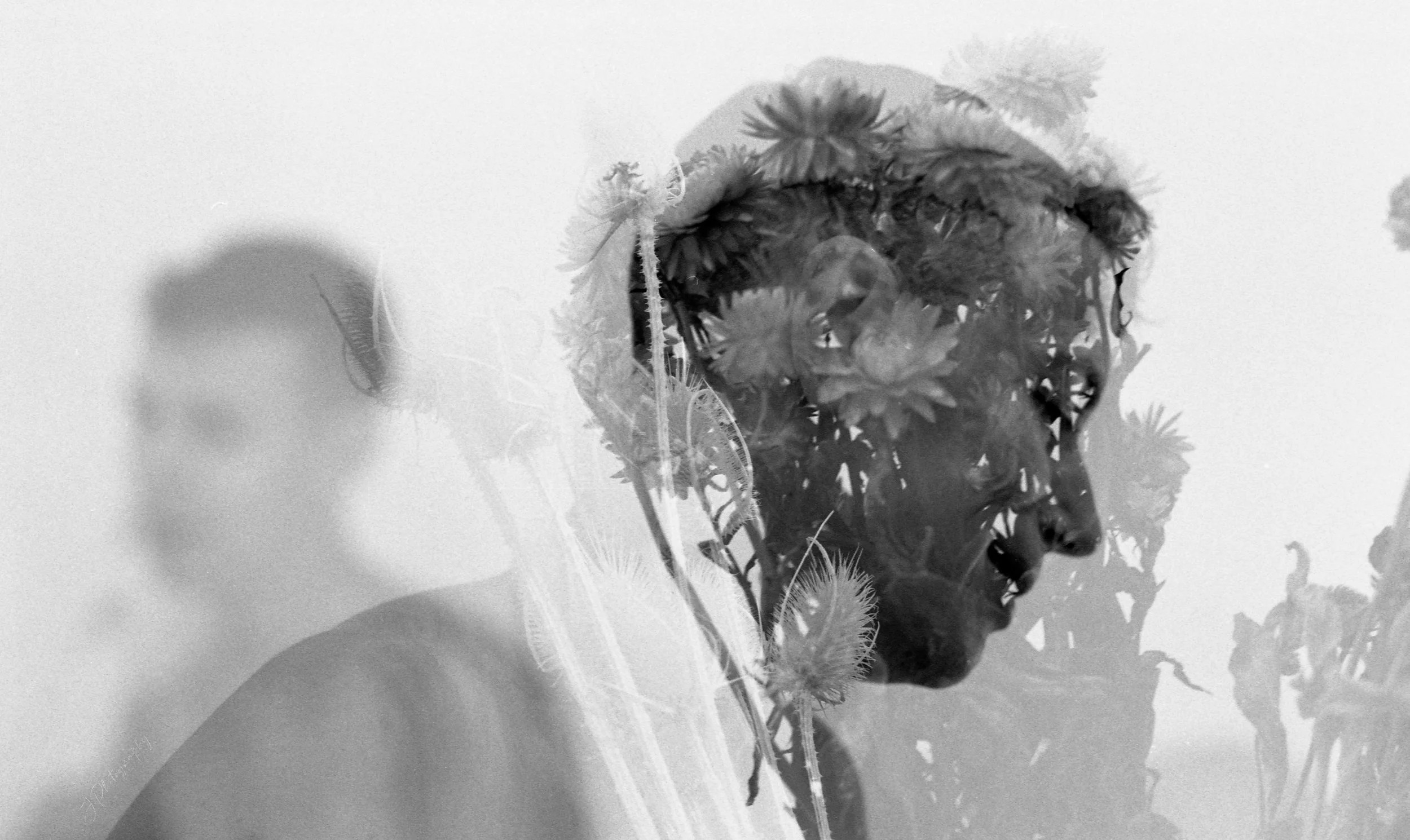 Une double exposition monochrome représentant une femme avec un visage sculpté et des fleurs dans ses cheveux. Le fond montre des silhouettes de personnes et des éléments architecturaux.