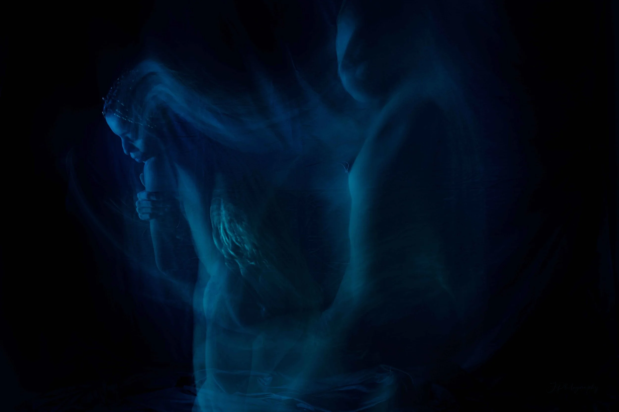 Une femme en méditation dans une lumière bleue diffuse et abstraite.
