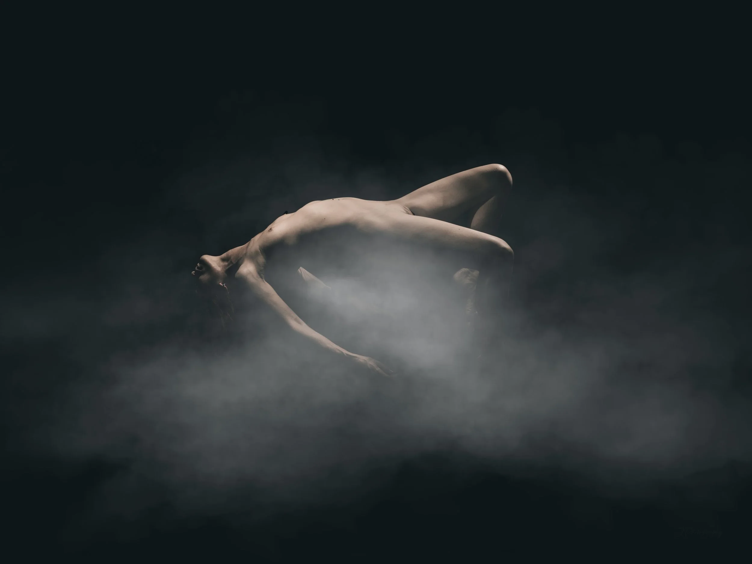 Technique de lévitation. Superbe composition de nu artistique, avec une ambiance mystérieuse, une lumière qui semble envelopper la modèle avec un brouillard gris. 