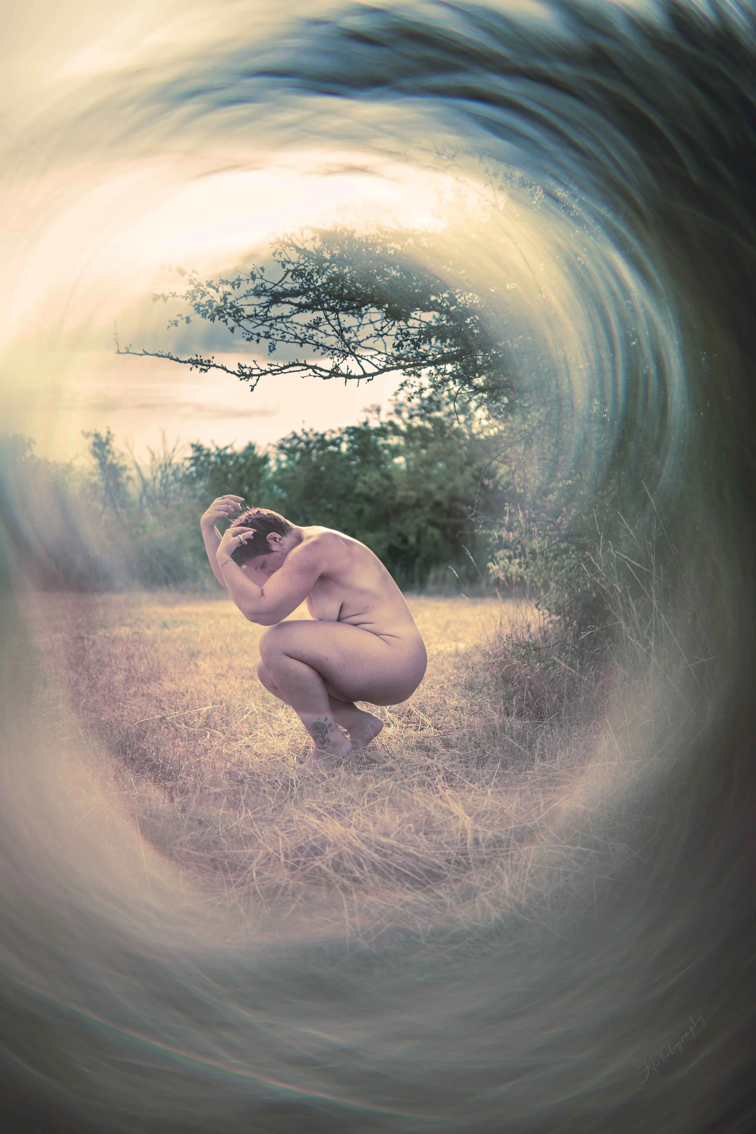 Une personne nue en position accroupie dans un champ avec des arbres en arrière-plan, entourée d'un effet visuel de vortex ou de spirale.