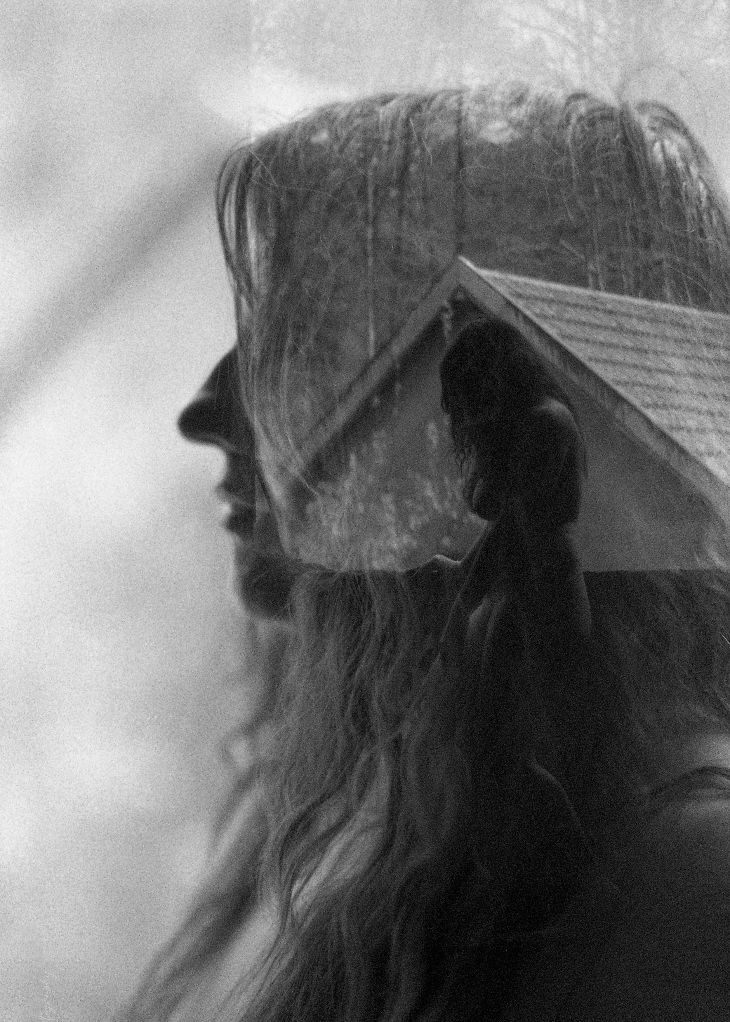 Portrait en noir et blanc d'une femme avec reflet de l'extérieur dans ses lunettes, créant une image double.
