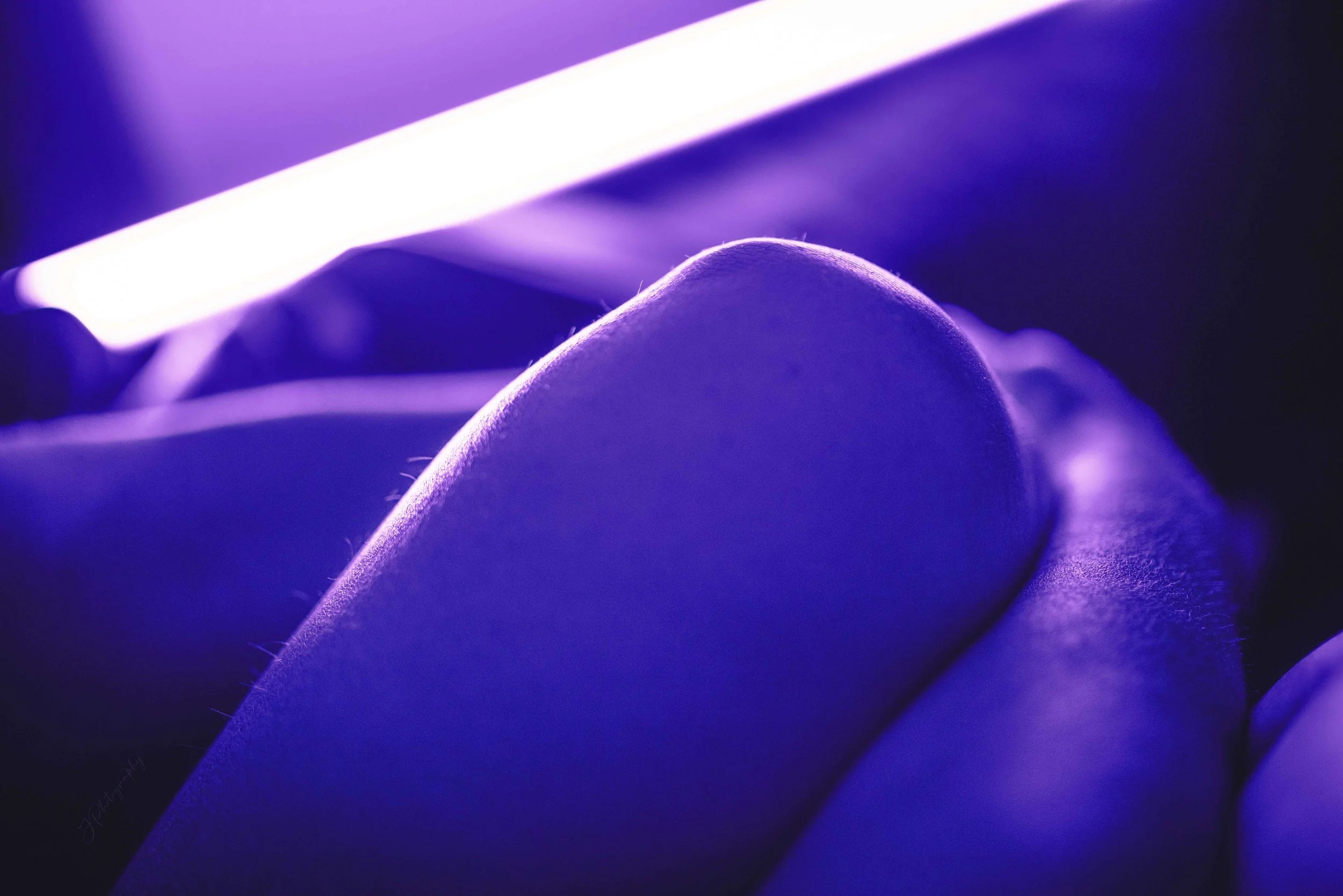 Gros plan sur une main humaine avec des doigts pliés, éclairée par une lumière violette.