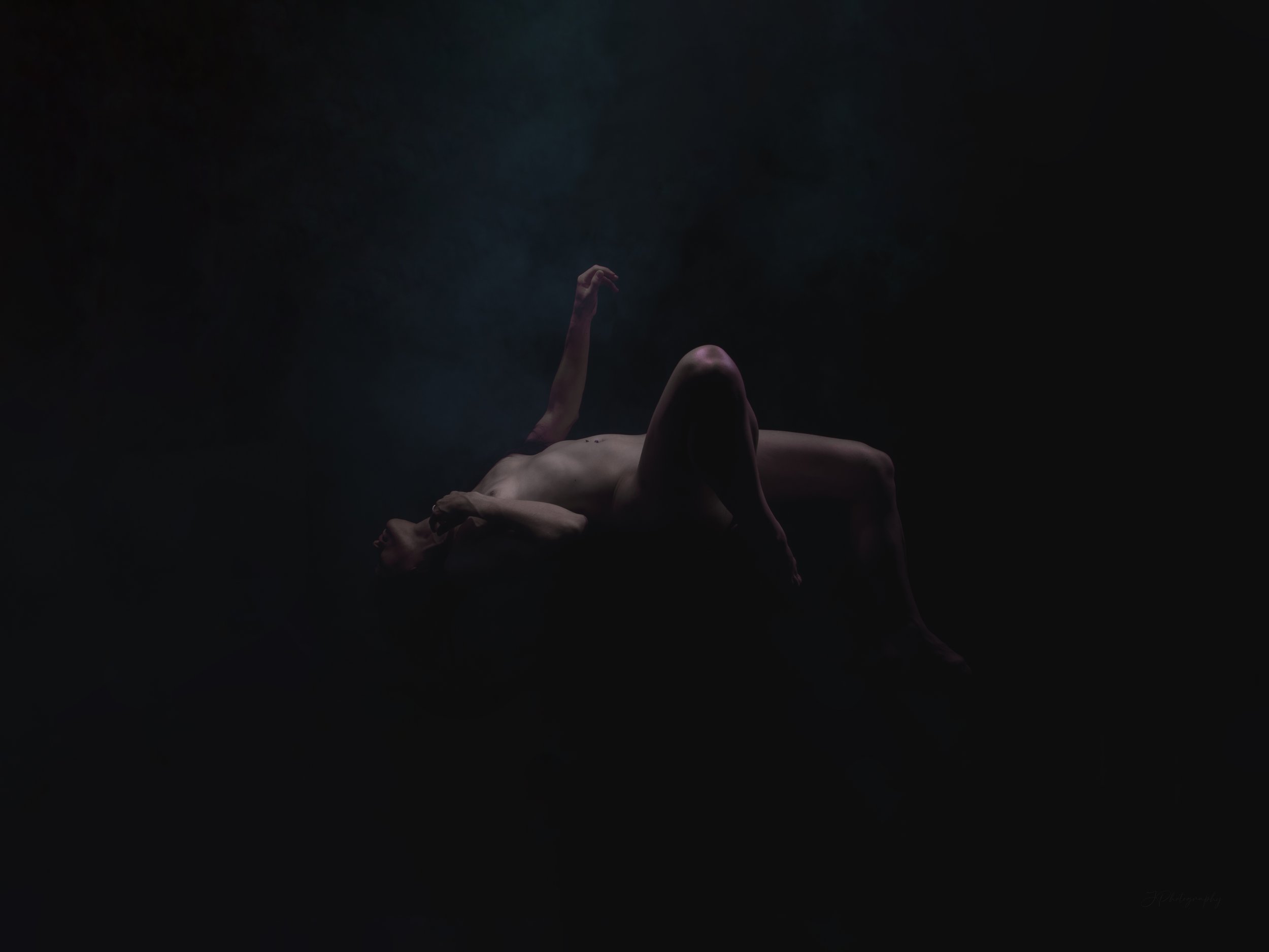 Technique de lévitation. Superbe composition de nu artistique, avec une ambiance légèrement inquiétante, une lumière qui semble envelopper la modèle avec un brouillard bleu. 