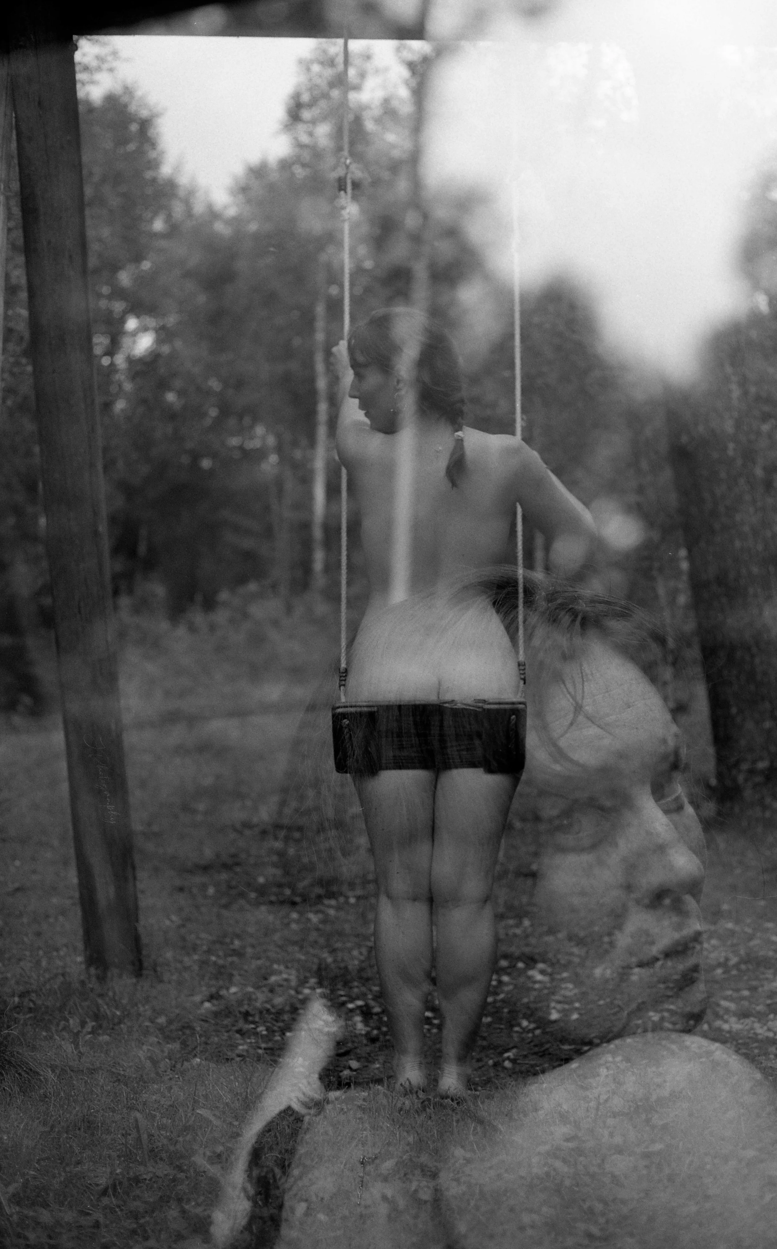 Une photo en noir et blanc d'une fille nue assise sur une balançoire dans une forêt, avec l'image d'une autre femme en superposition.