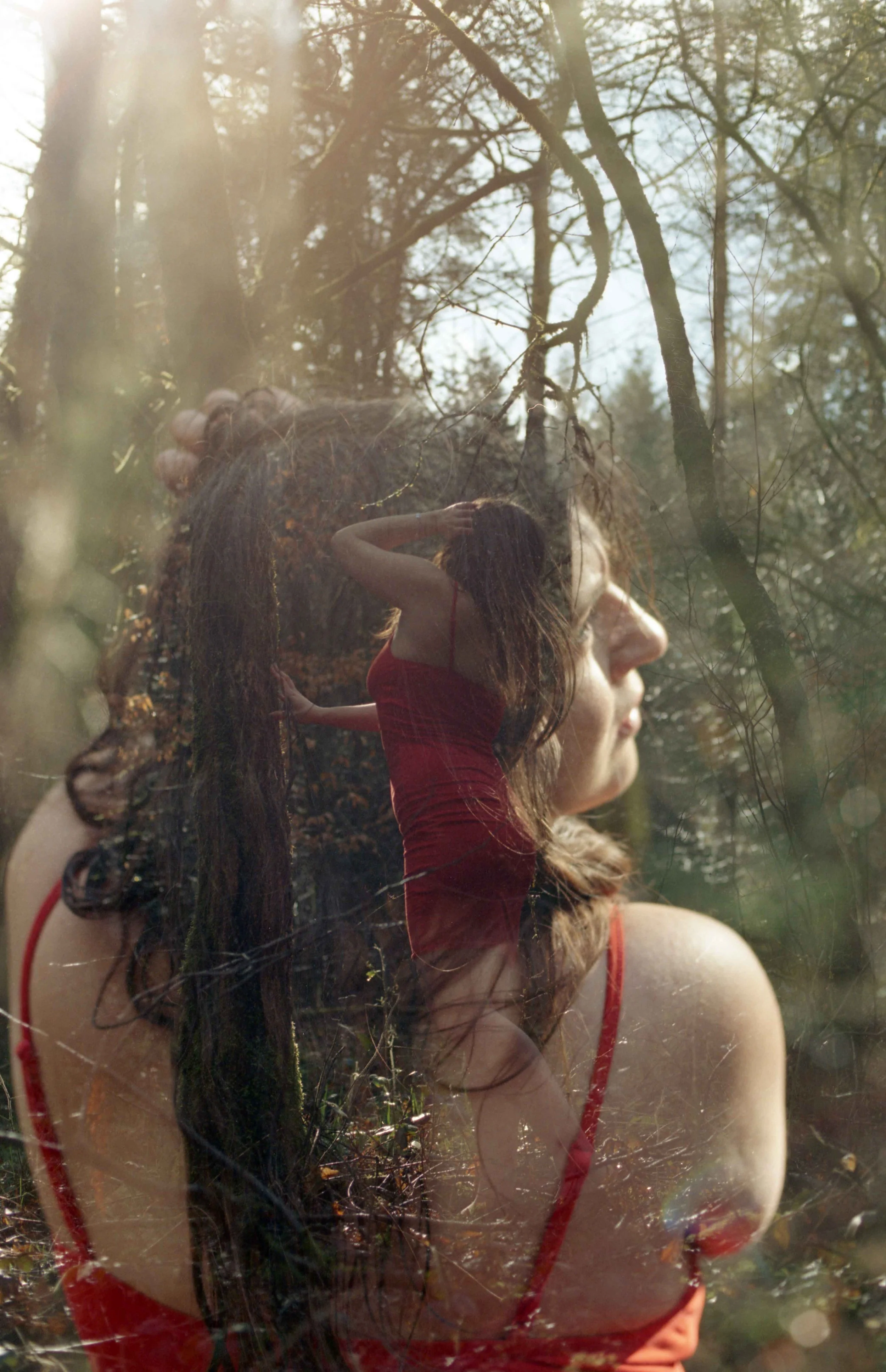 Une double exposition combinant une femme en robe rouge dans la forêt avec des branches, créant une image artistique.