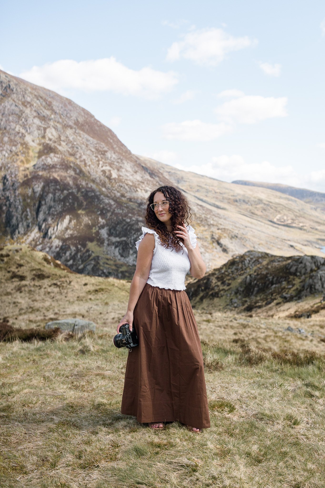 Wedding photographer holding her camera in the mountains of North Wales.
