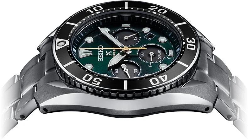 Close-up of a Seiko wristwatch with a black and silver bezel, green dial, multiple subdials, and a silver metal band.