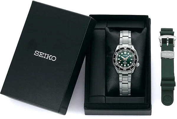 Seiko wristwatch in a black box with an additional green strap next to it.