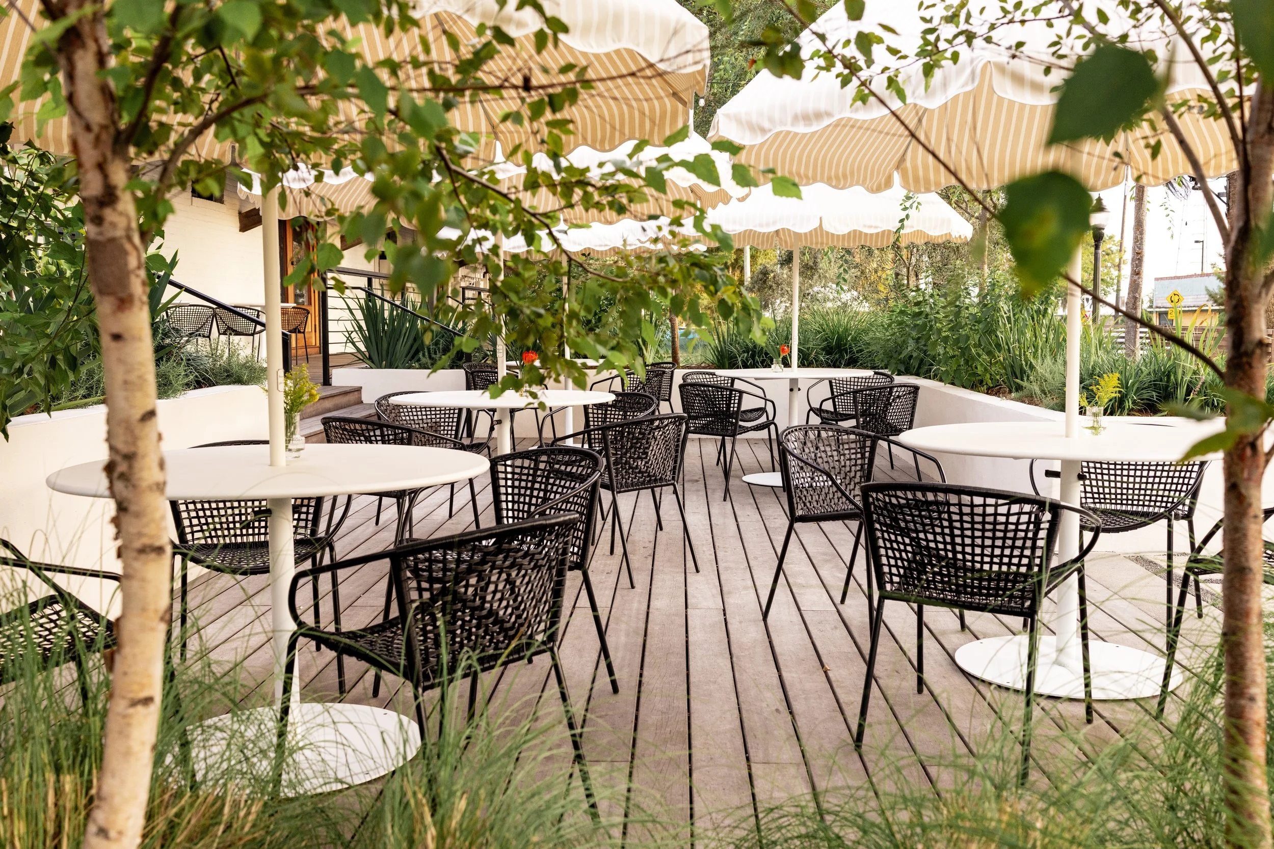  empty dining deck with 5 tables, 5 chairs at each table, and umbrellas. comfortably seats large parties. 