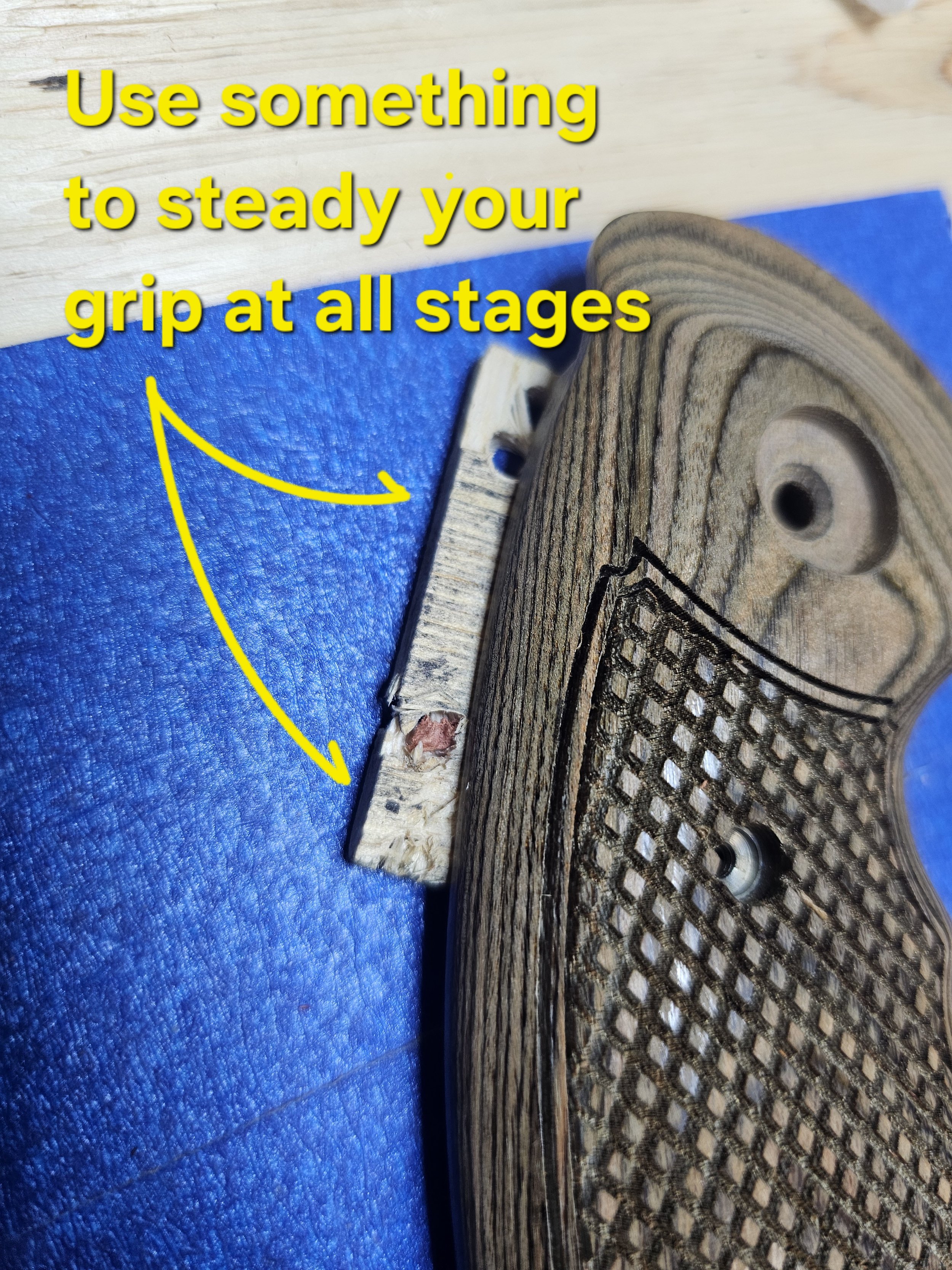 Close-up of a wooden object with a textured grip, resting on a blue fabric background, with overlaying yellow text that says 'Use something to steady your grip at all stages' and an arrow pointing to the object.