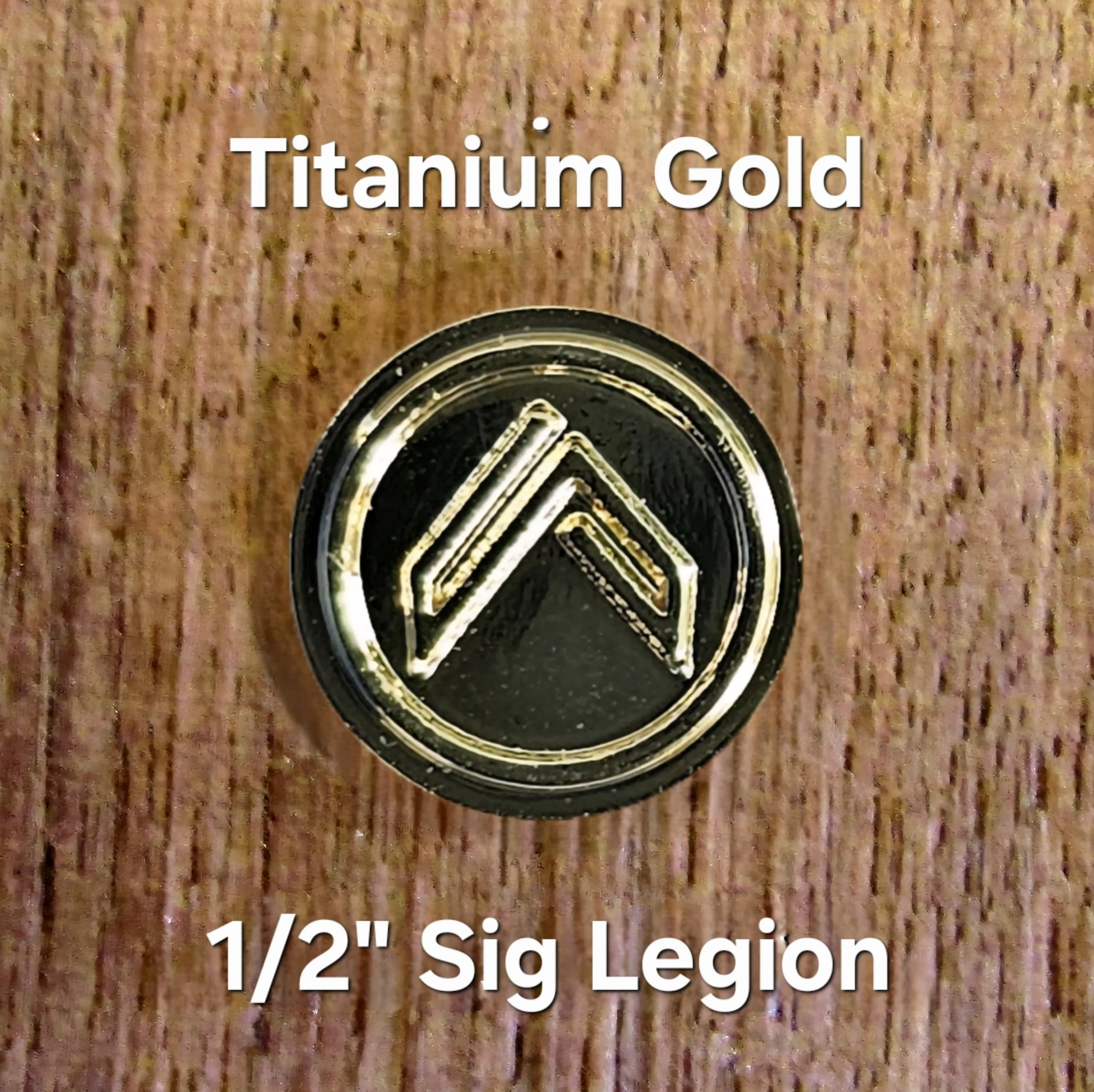 Close-up of a circular badge with black and gold design, partially visible, on a textured brown surface. Overlaid text says 'Titanium Gold' and below it '1/2" Sig Legíon'.
