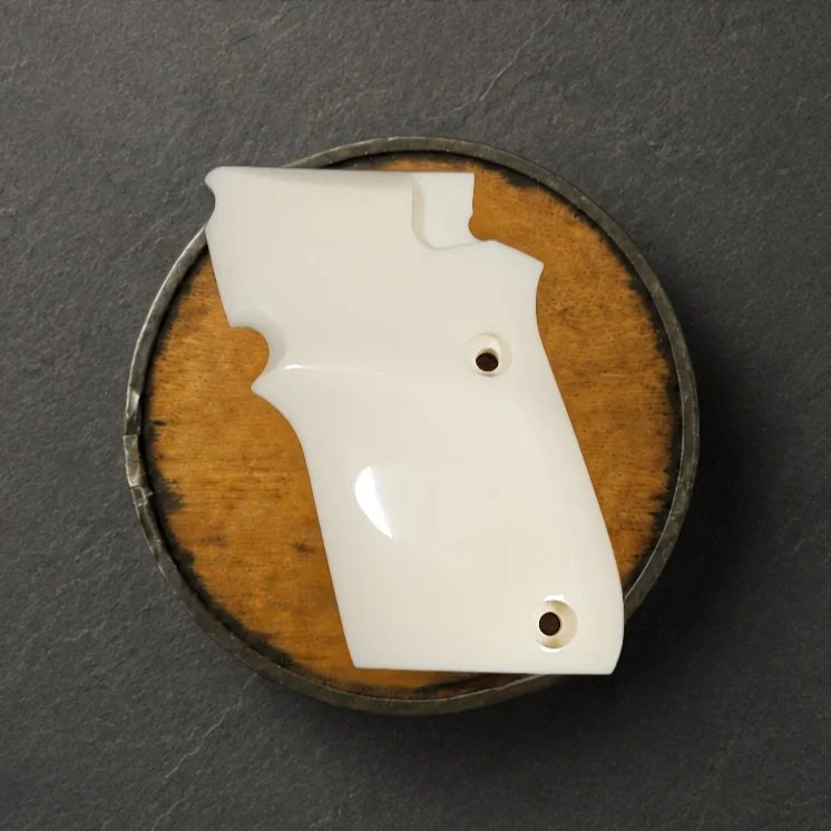A wooden pistol grip with carved details on a black surface.