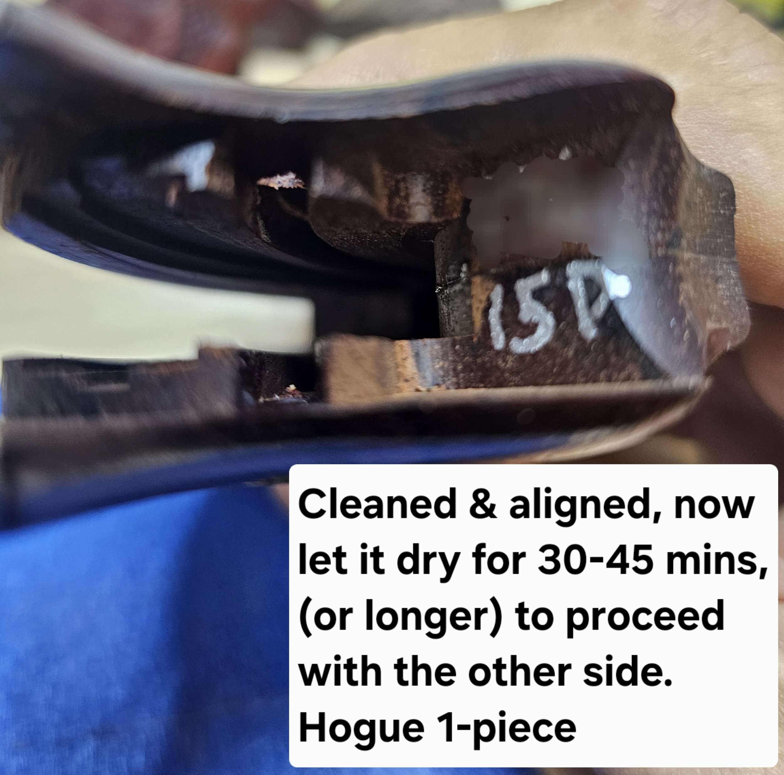 Close-up of a black object with a hole, positioned on a surface with blue and beige colors. There is partial text visible on the object, including the words 'Cleaned & aligned' and instructions about drying. The image captures a detailed view of the object and part of the surrounding surface.