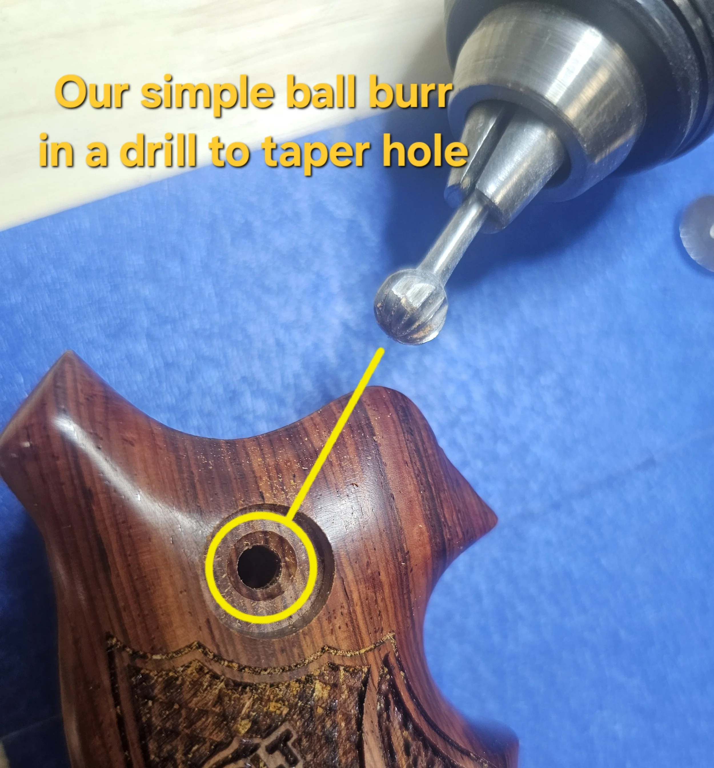 Close-up of a wooden hand-shaped object with a hole that is being drilled, showing a drill bit in the process of creating the hole.