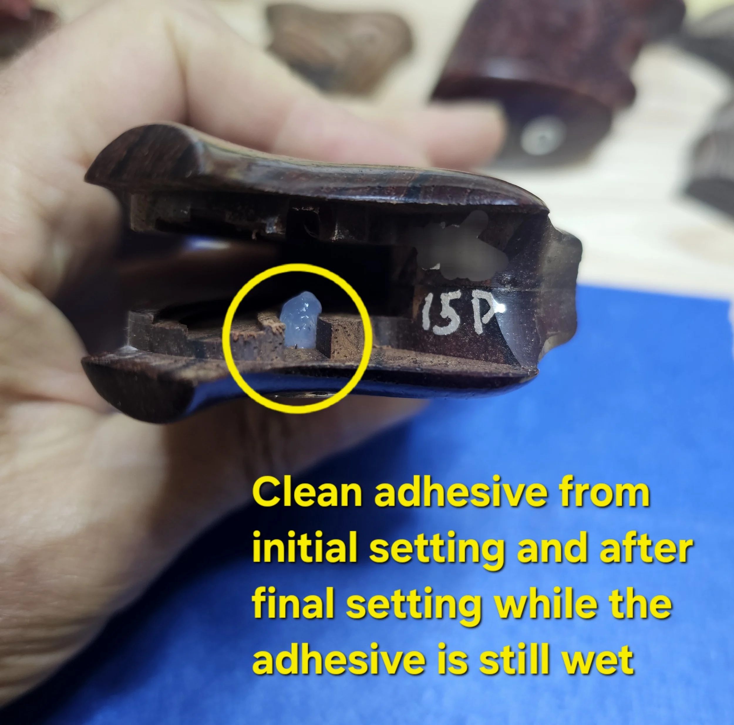 Close-up of a hand peeling blue adhesive from a surface, with instructions about initial and final setting. The text discusses cleaning adhesive from the surface and the adhesive still being wet.