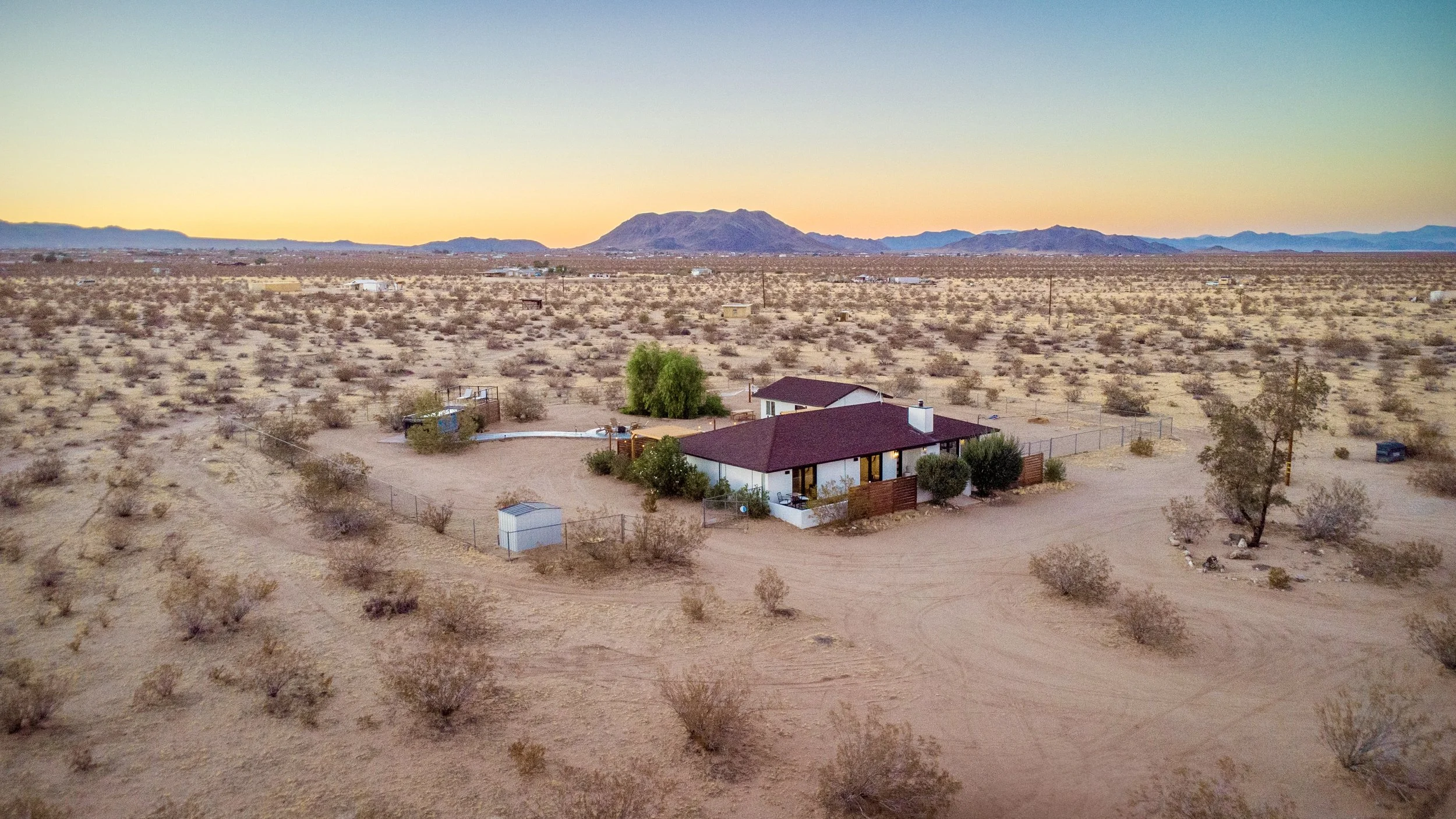 Front aerial view of Stargazer Getaway on five private desert acres with mountains in the distance.