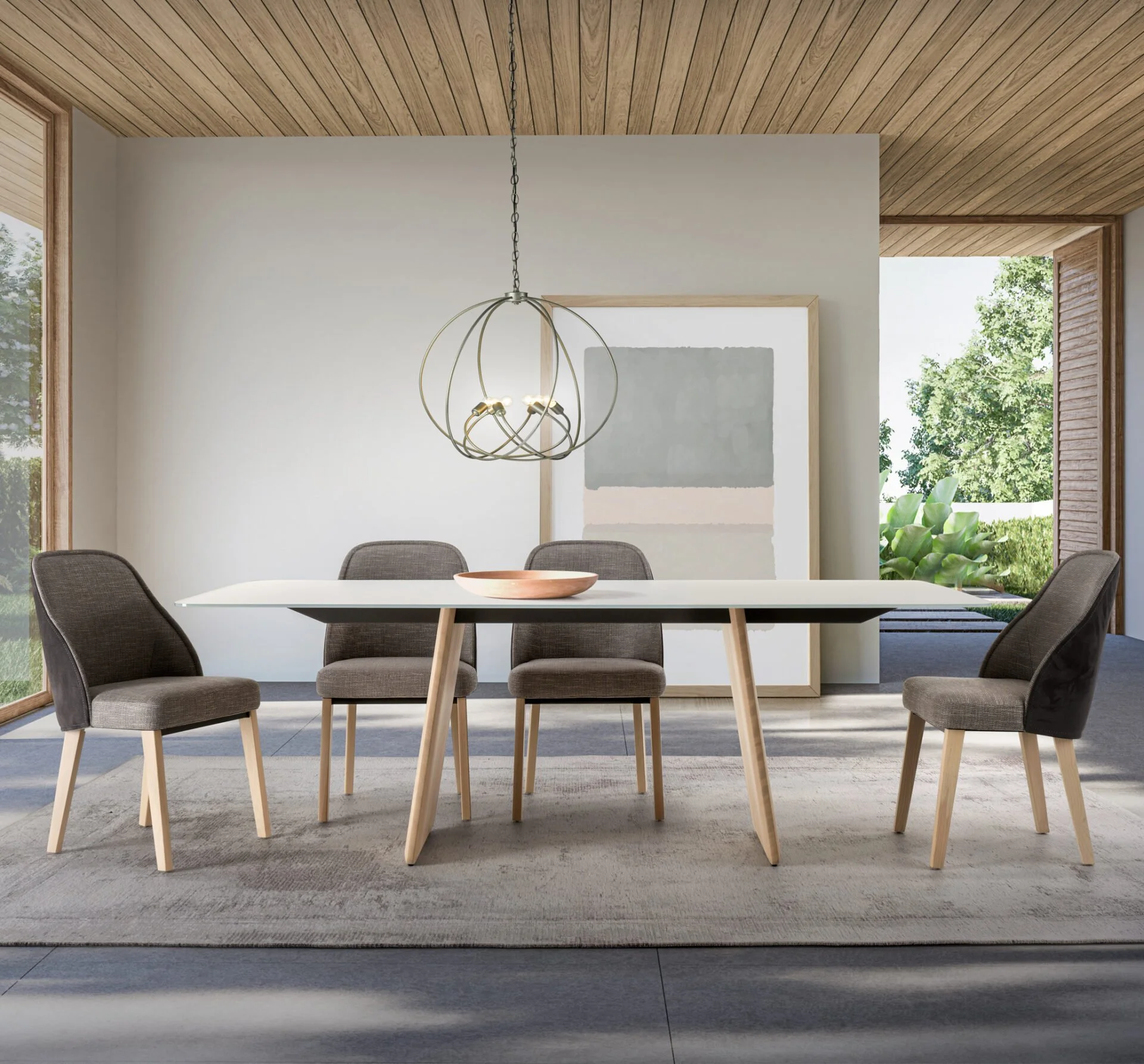 Modern dining room with a white table, four upholstered chairs, a decorative pendant light, wall art, large windows with views of green trees, and a wooden ceiling.
