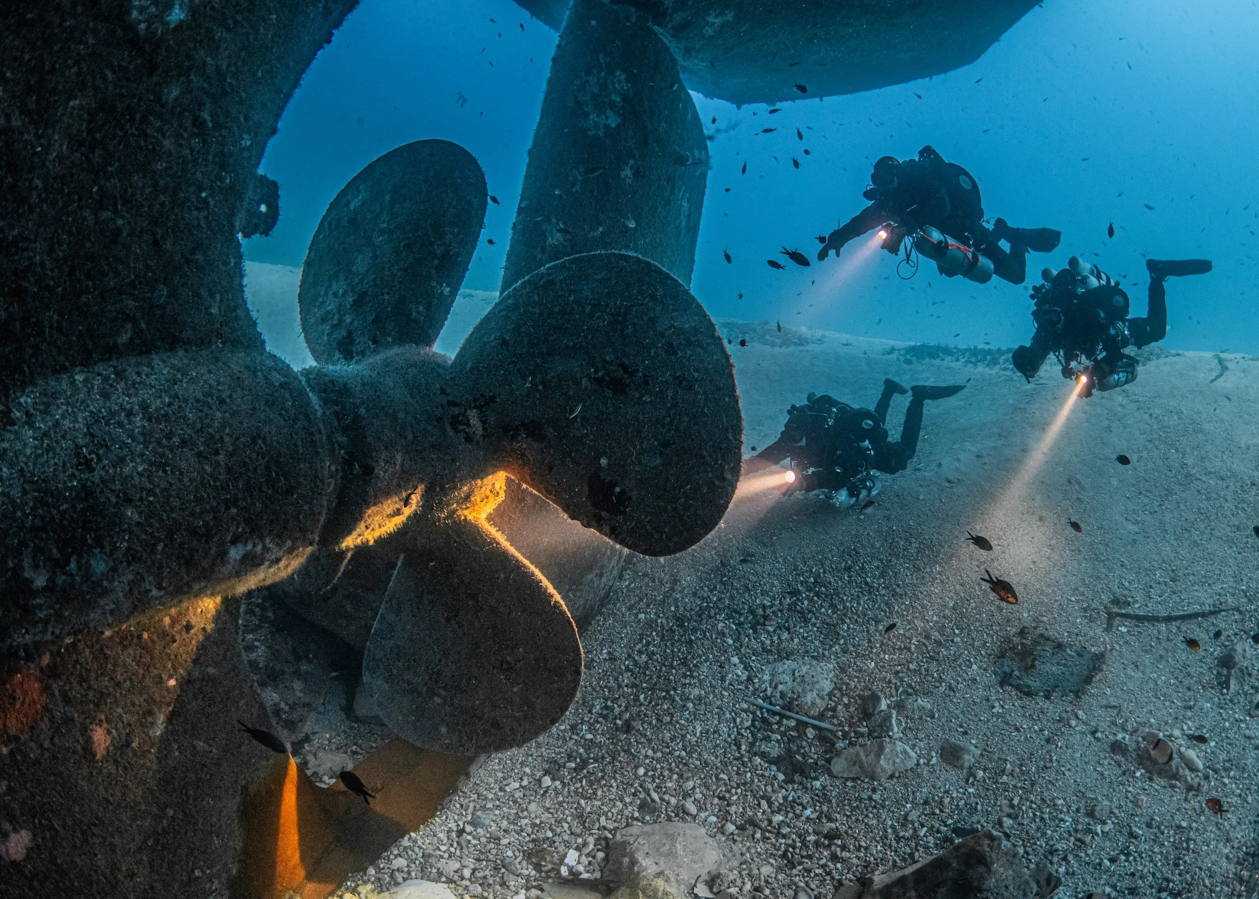 GUE divers at the propeller of the Um El Faroud wreck dive site in Malta.