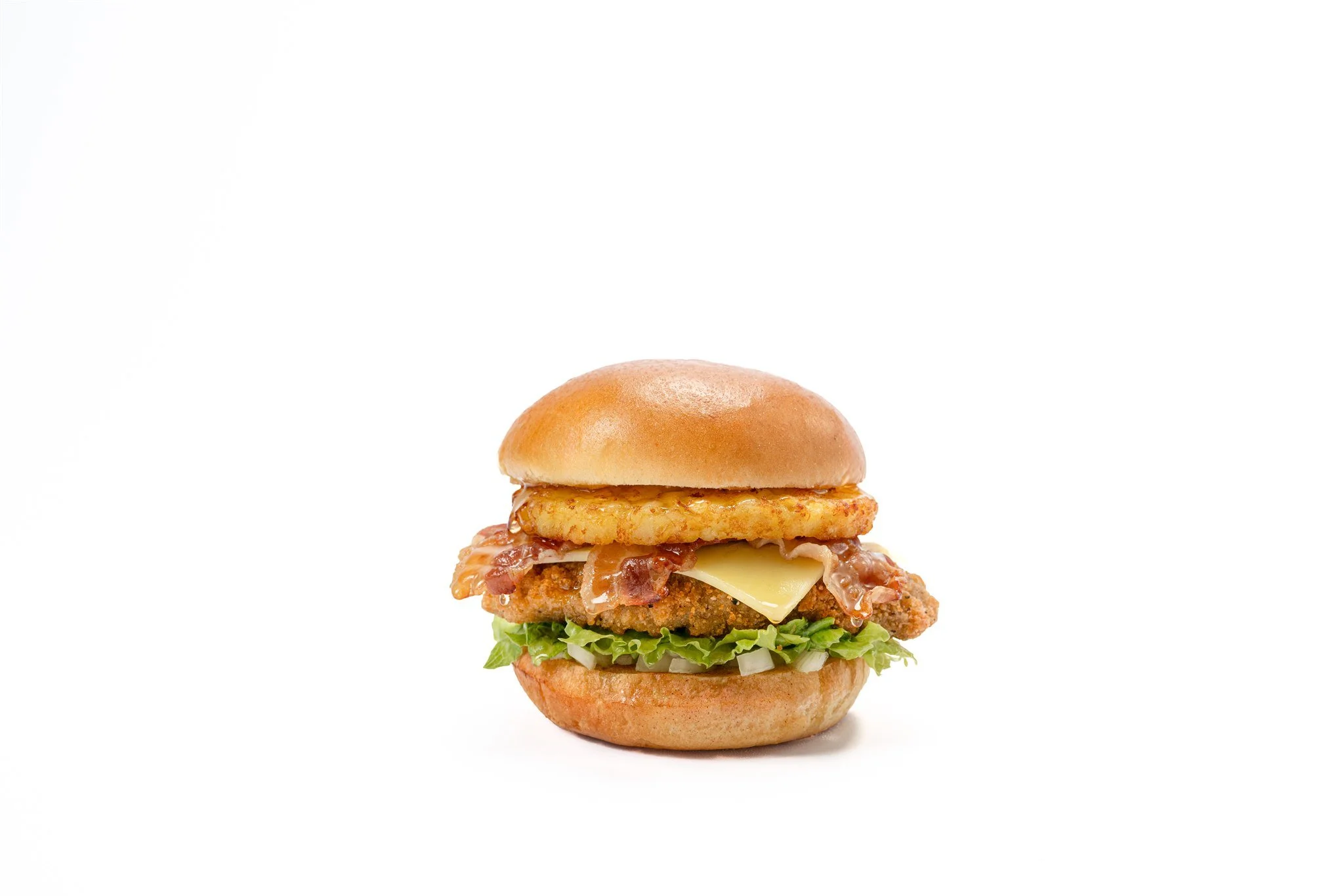 A chicken sandwich with lettuce, a fried chicken patty, a slice of cheese, an onion ring, bacon, and a sandwich bun.