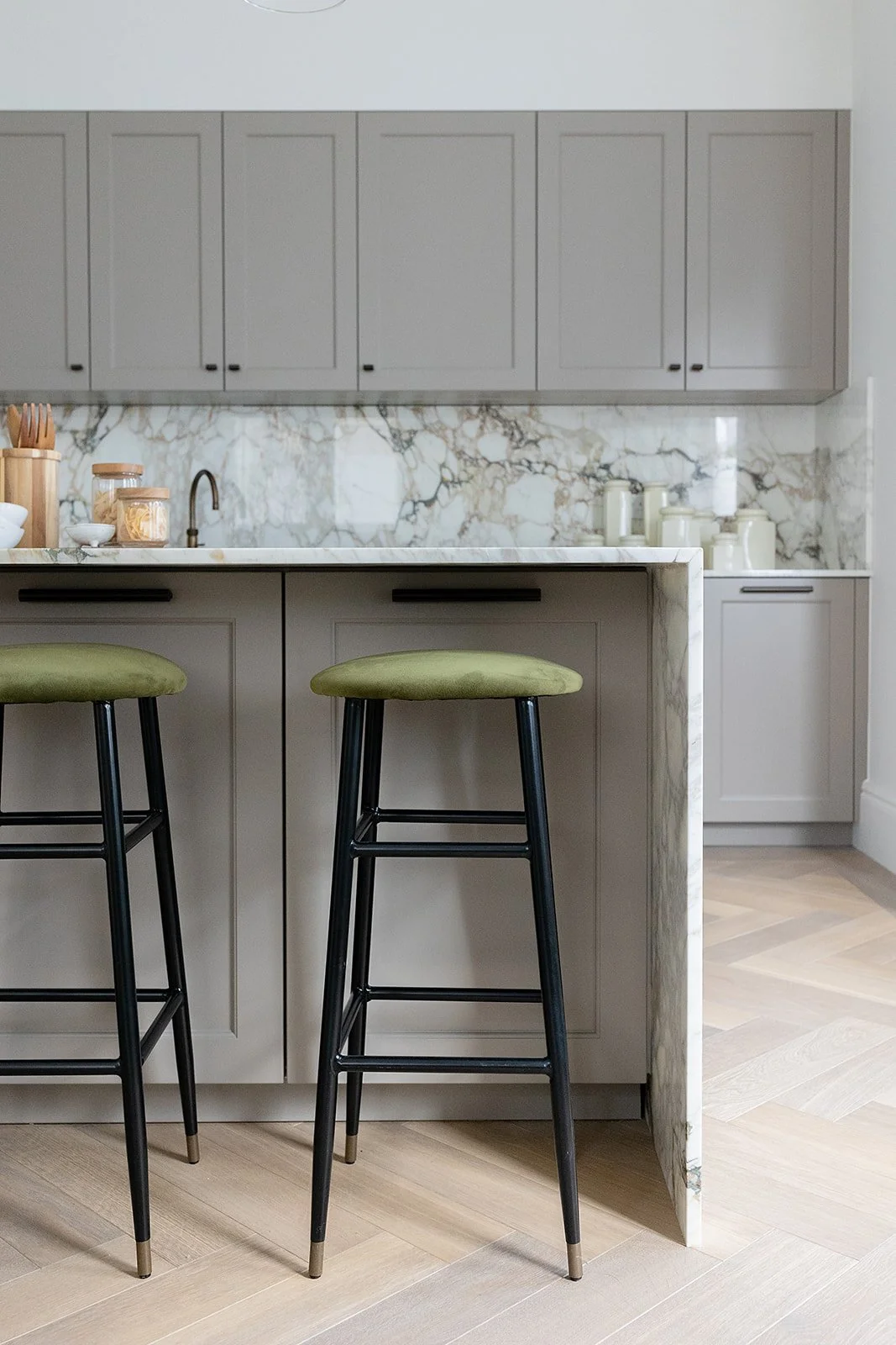 angle of the inside of a breakfast bar with green stools and granite surfaces at a london mansion