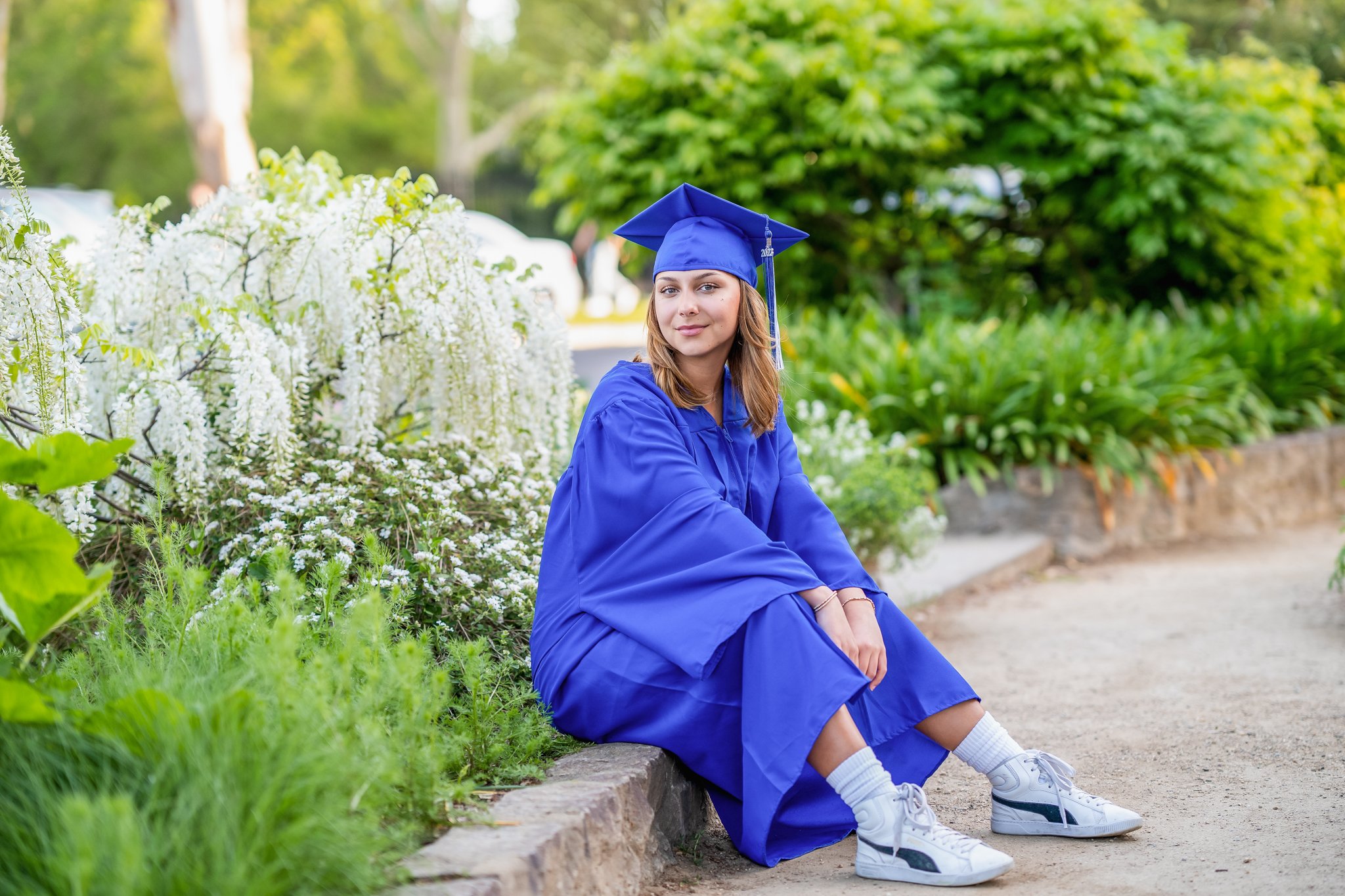 A young man with short dark hair, smiling, sits behind a red jacket with a white Alabama 'A' logo, leaning on his crossed arms.