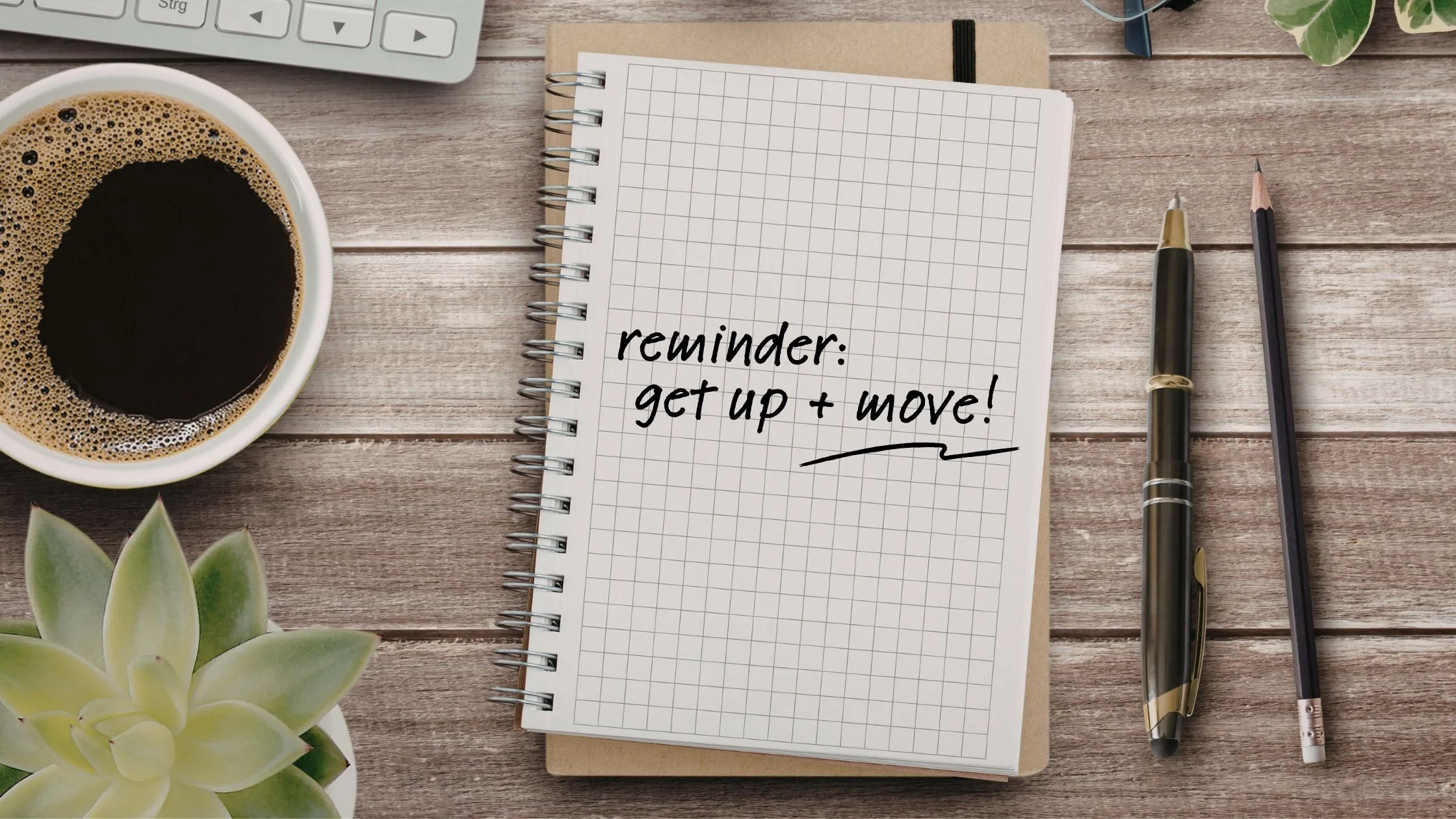 A flatlay image of a work desk with a pen, pencil, cup of coffee, a laptop, and an open notebook with "Reminder: get up and move!" written on the page.