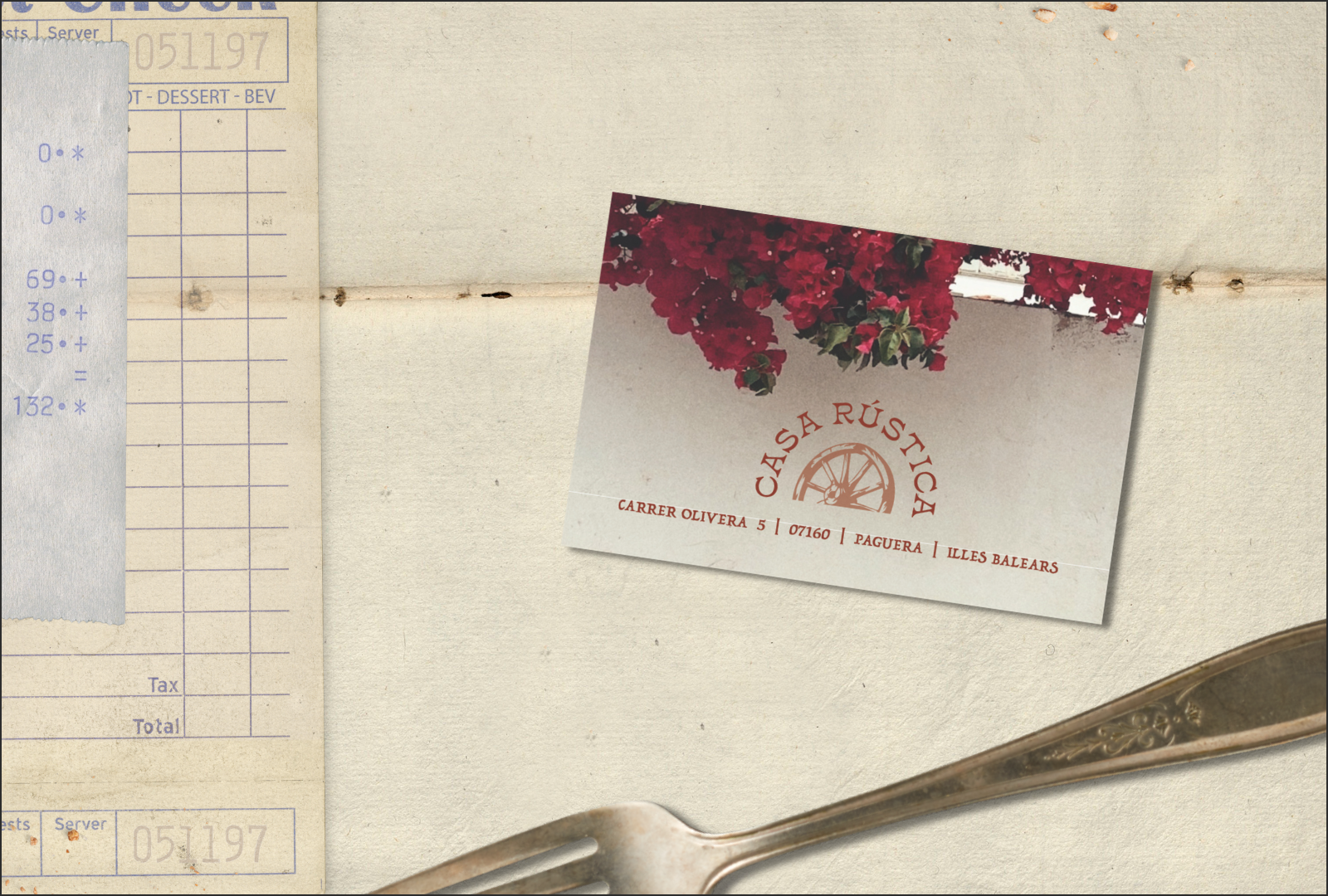 A business card for Casa Rústica with contact details, pinned to a wall above a fork.
