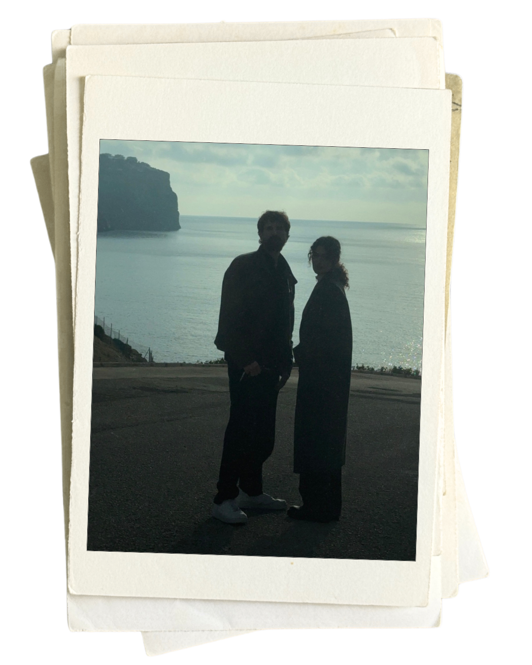 Silhouetted man and woman standing by the coast with the ocean and cliffs in the background