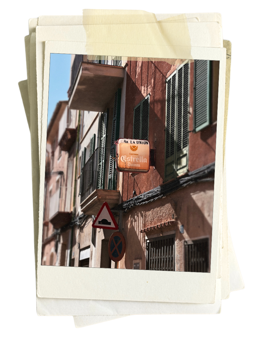 Street view of a building with green window shutters, balconies, and a sign for Estrella Damm beer. Two road signs are visible, one indicating a speed bump and the other indicating no parking.