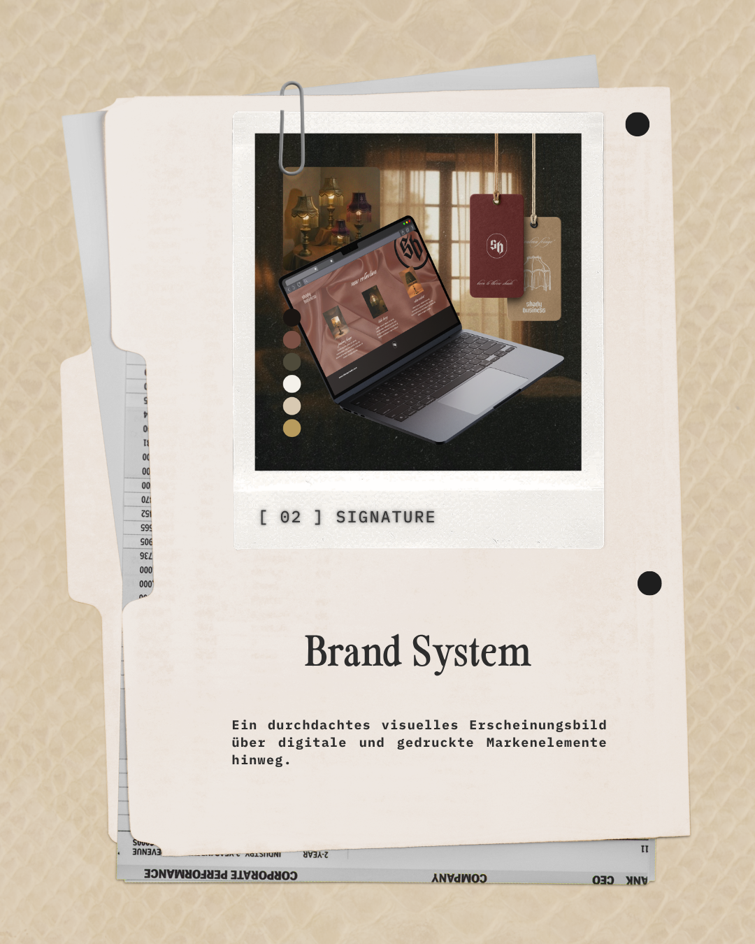 A printed sheet labeled 'Brand System' featuring a digital and printed elements concept, with a photograph of a laptop displaying a website, hanging tags, and blurred background of lit lamps.