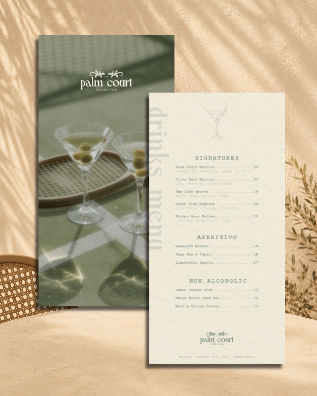 A menu from Palm Court Social Club featuring drink options for signatures, aperitivo, and non-alcoholic beverages, with a background of two martini glasses with green olives and sunlight reflections.