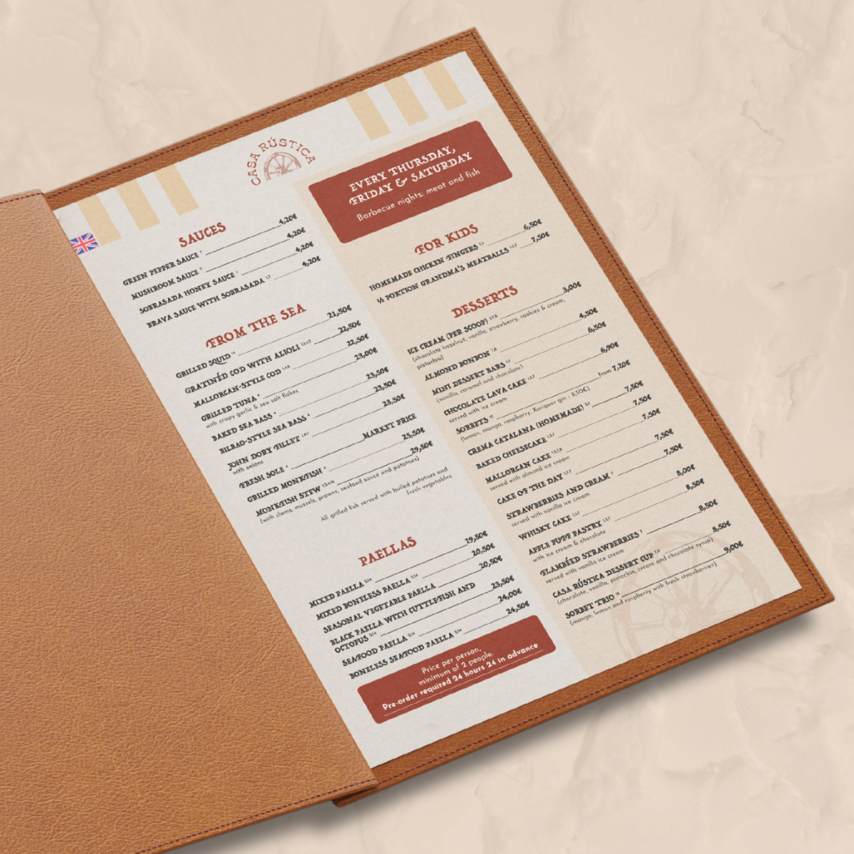 Restaurant menu with sections for sauces, from the sea, paellas, for kids, desserts, and more, inside a leather portfolio on a table.