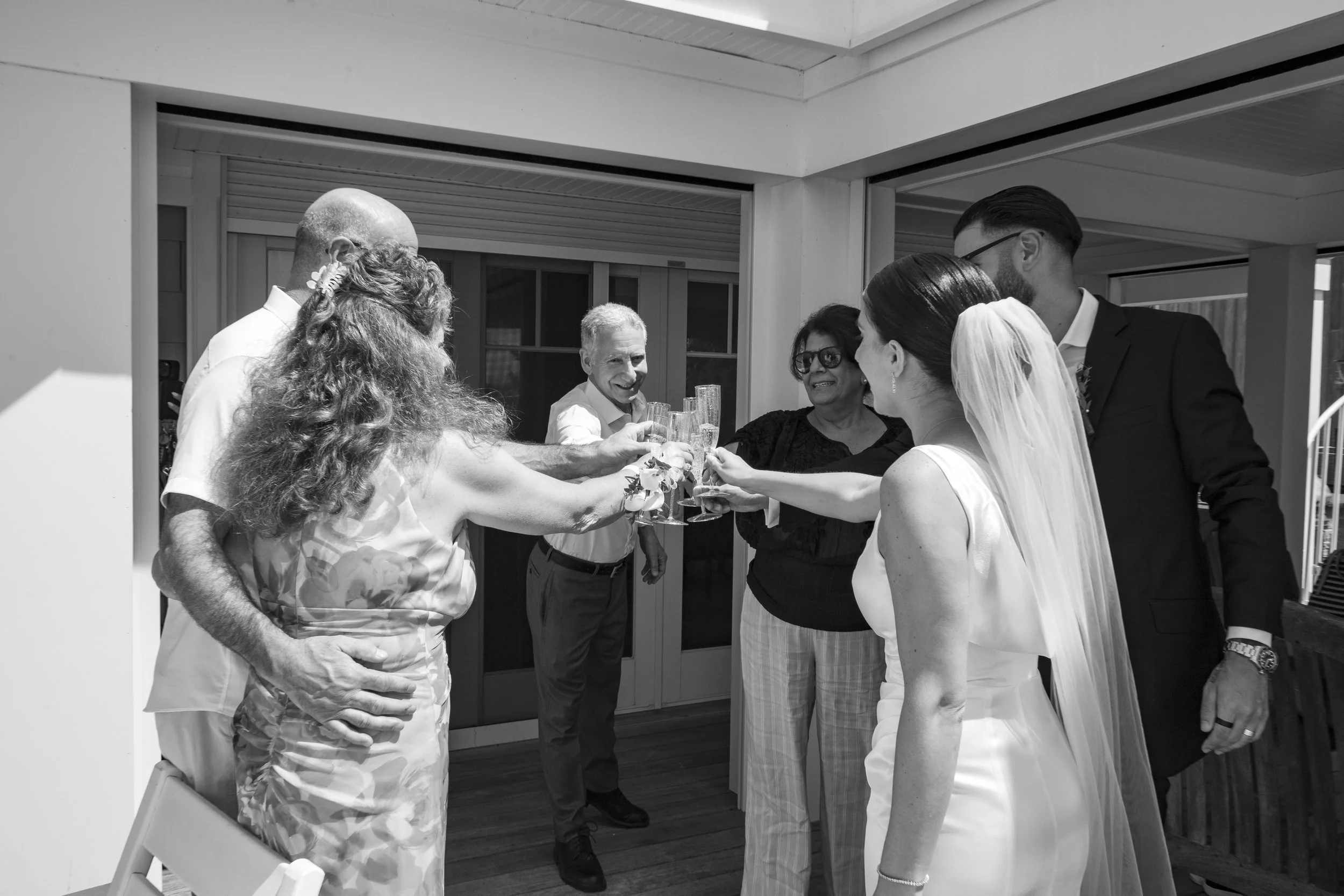 People celebrating at a wedding reception, holding glasses in a toast.