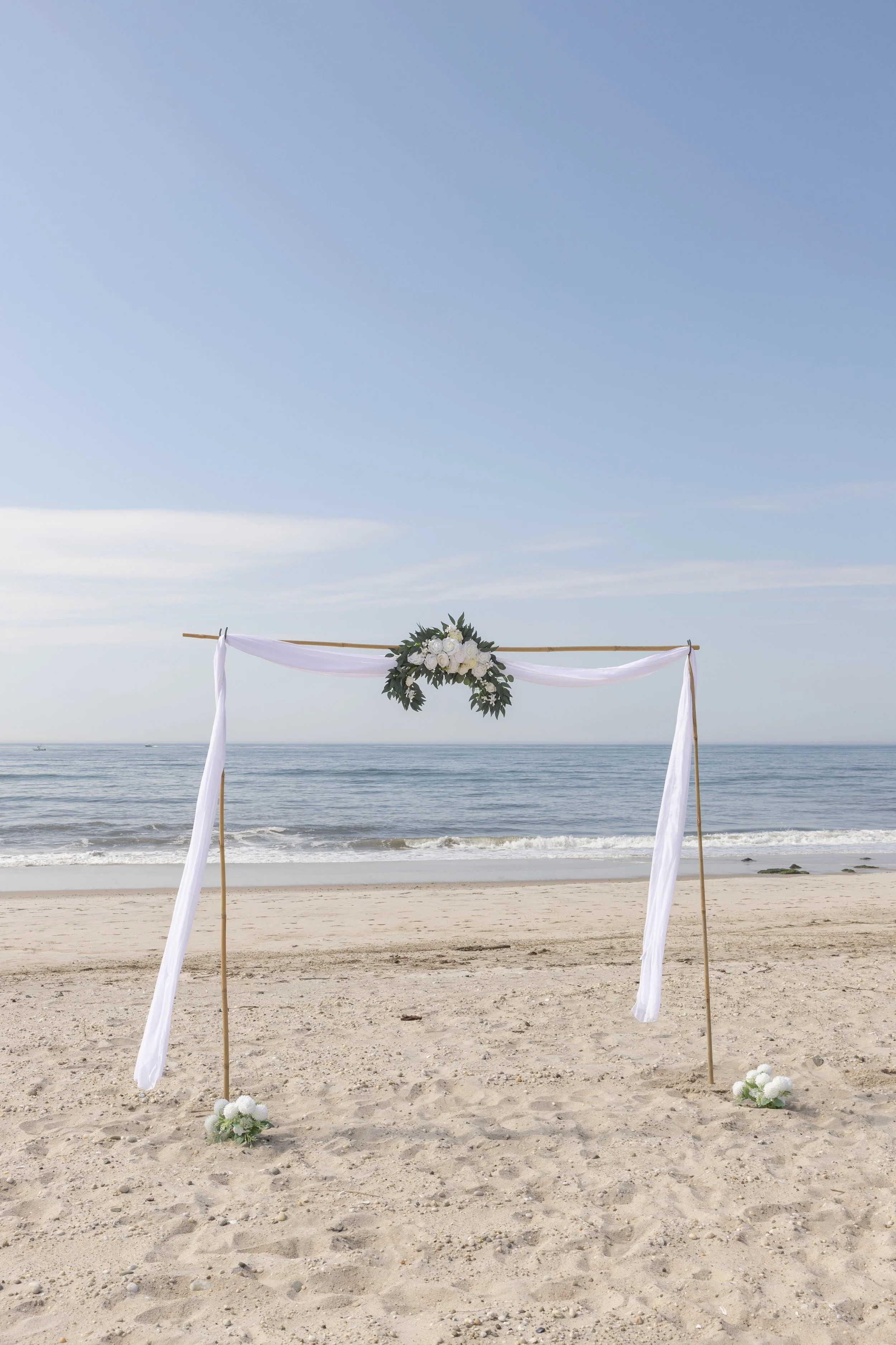 Romantic beach wedding arch with white draping and florals by Pop-Up Vows