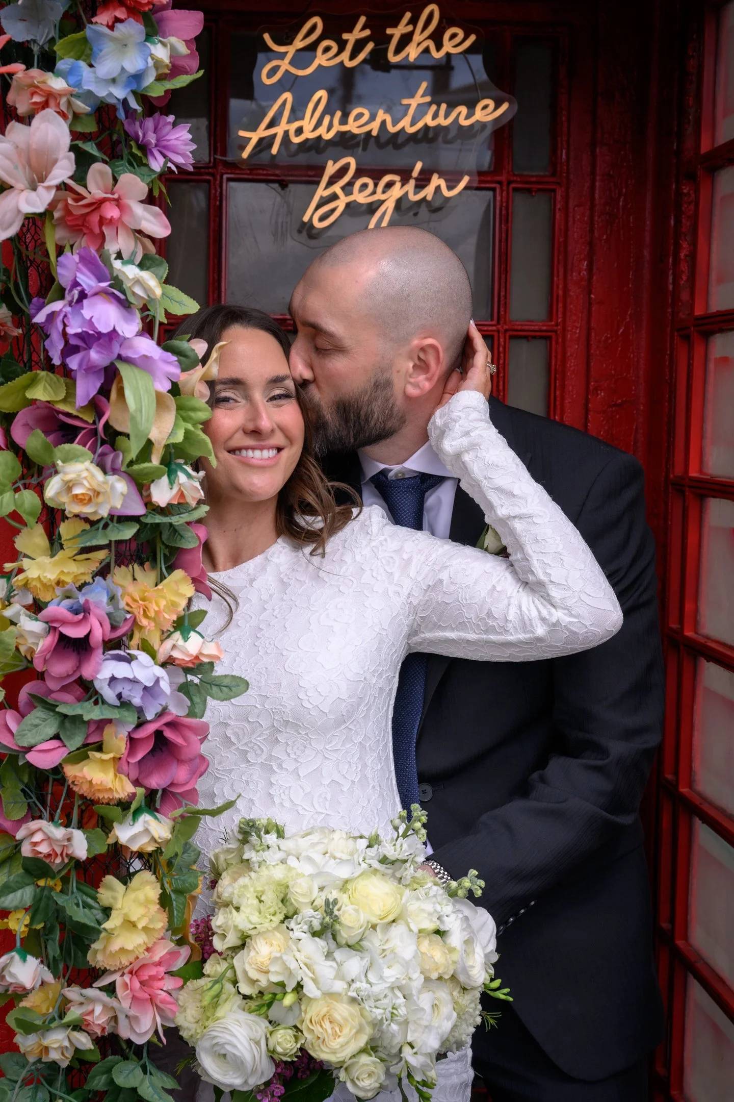 Couple smiling together beside colorful wedding florals during an intimate South Florida wedding.