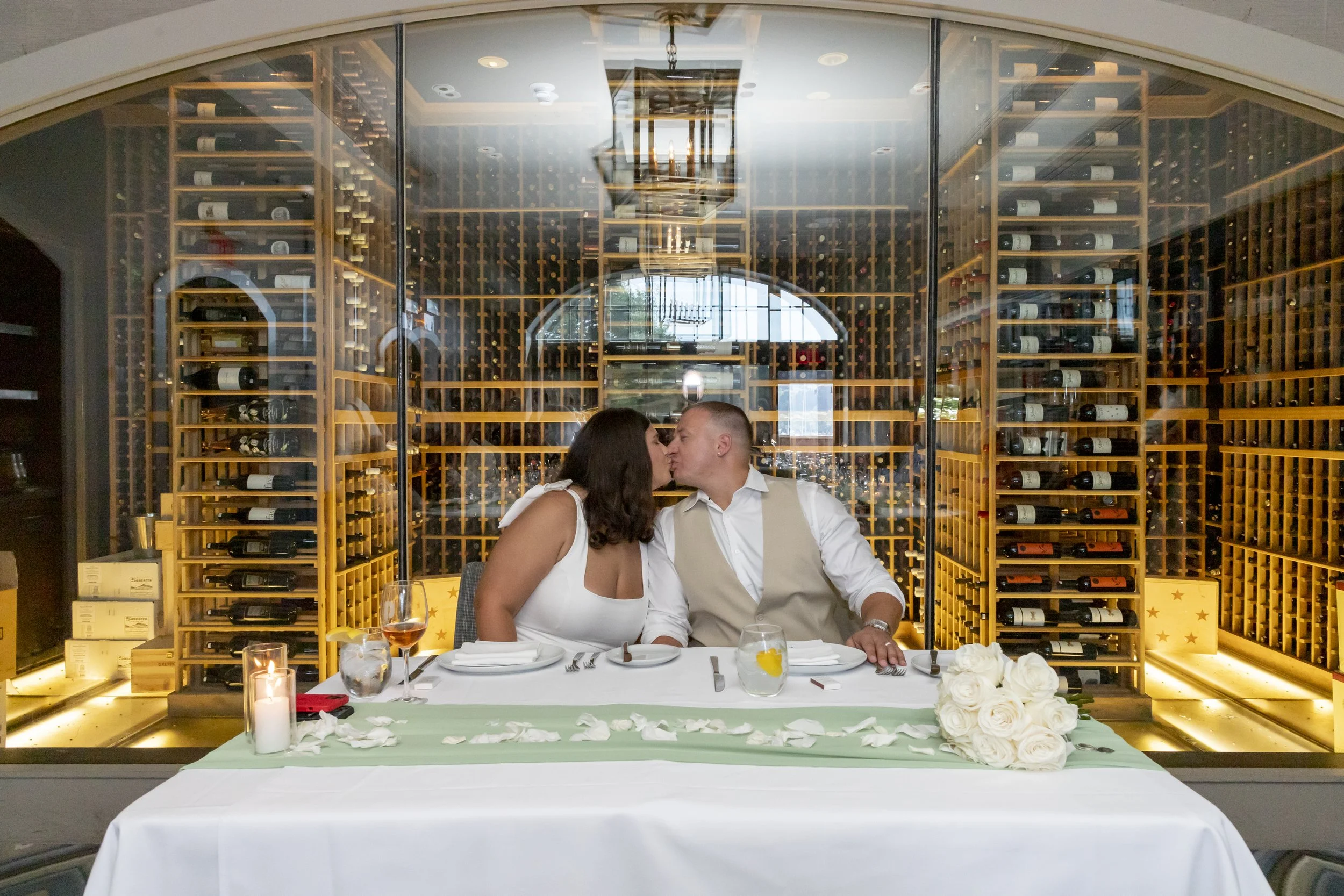 Private dining room micro wedding. Bride and groom kissing in the wine room.