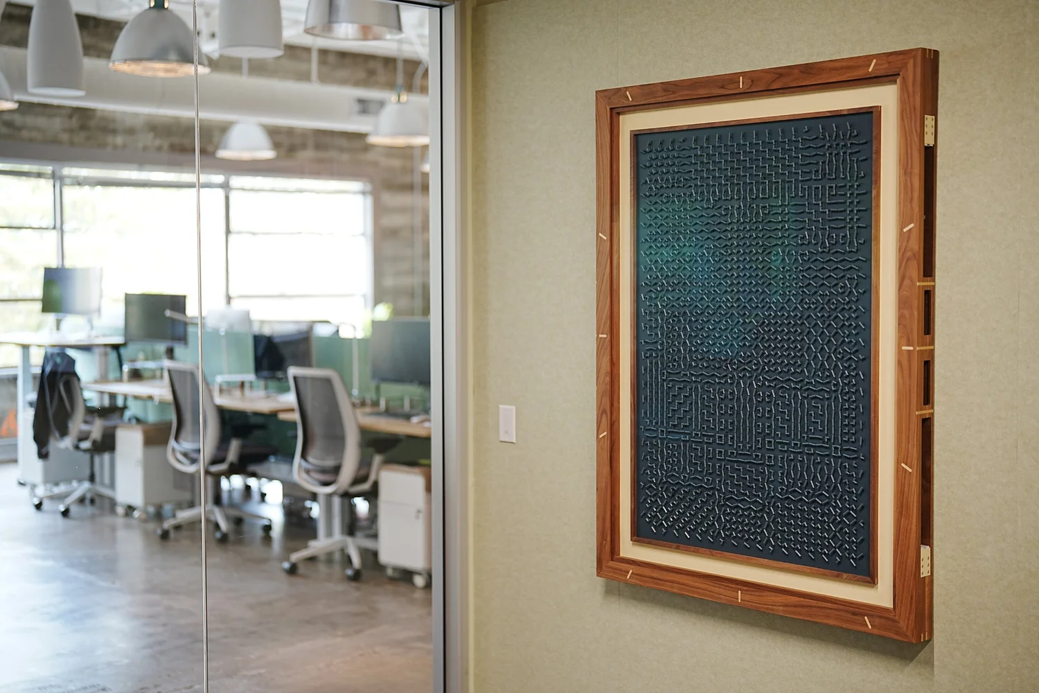 Empath hanging on an office wall: a walnut frame around a dark blue panel covered in a maze of small pieces