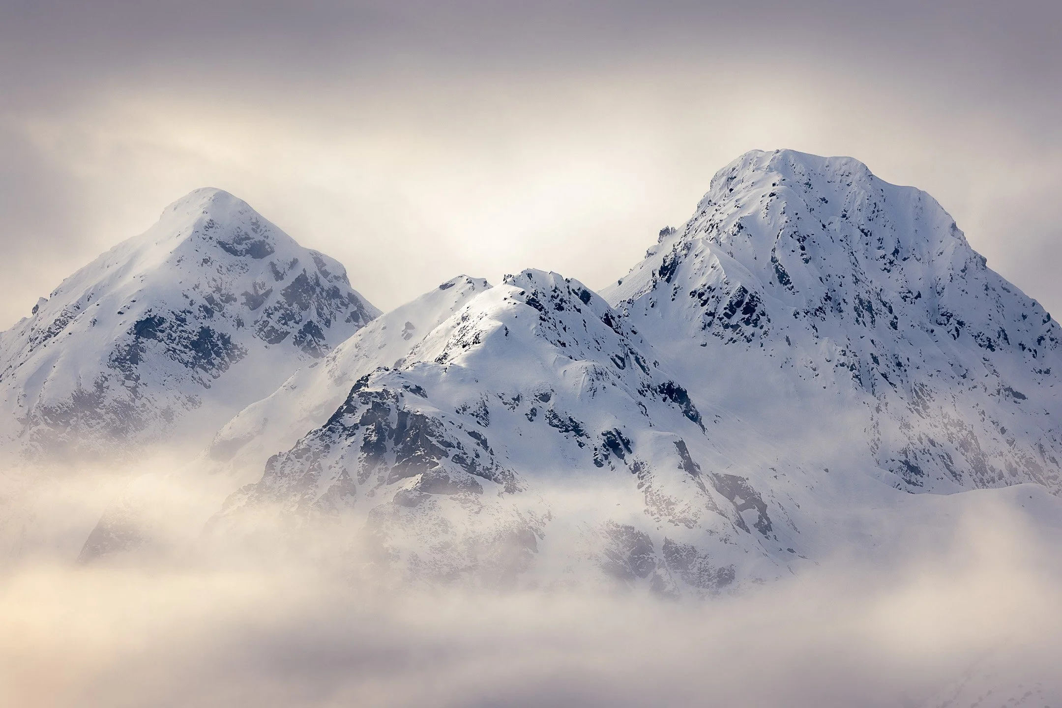 Three snow-capped peaks rise together through drifting cloud, Triplets, Fiordland, New Zealand