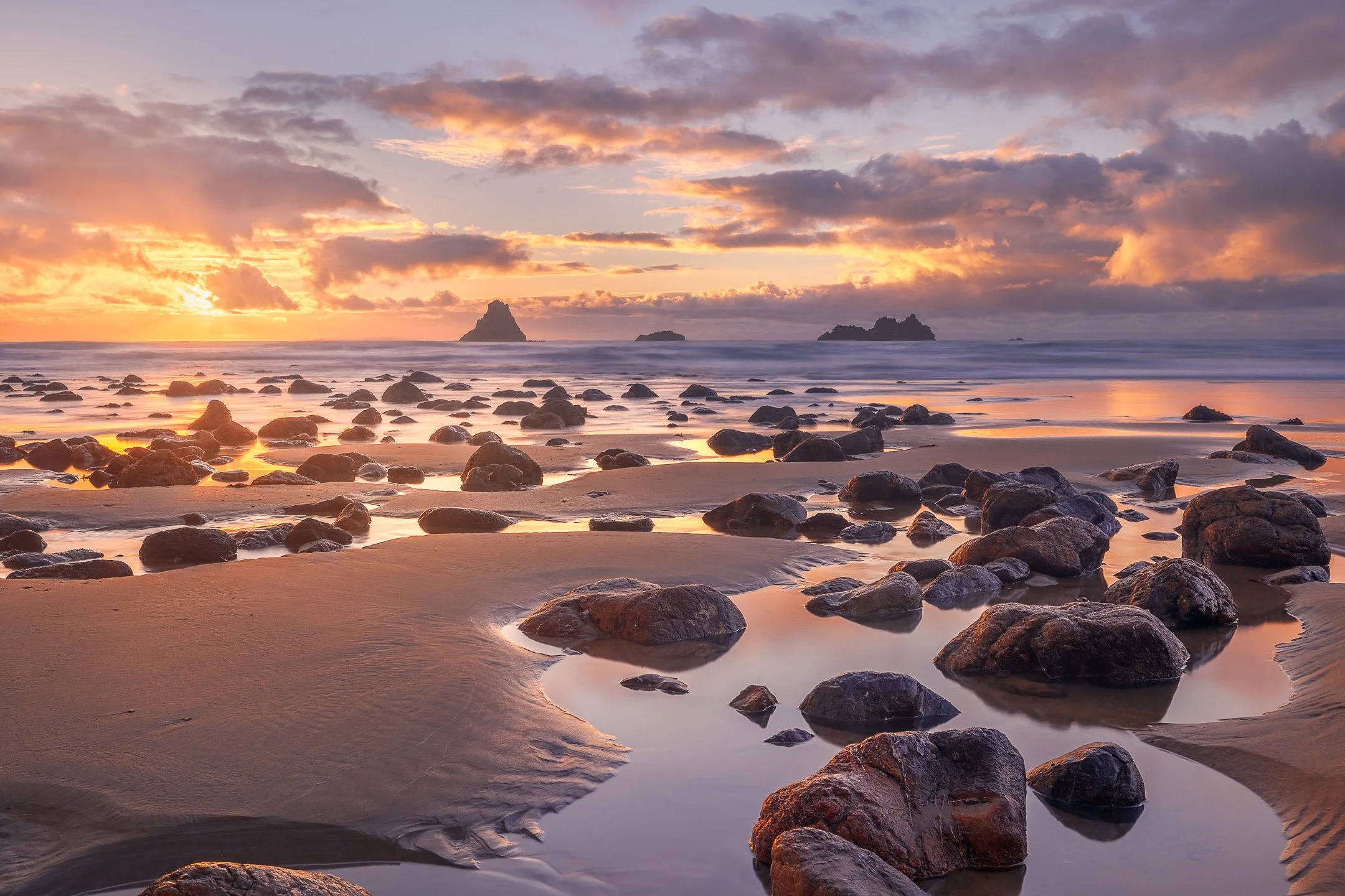 Warm sunrise colours wash over Kairakau Beach with the Hinemahanga Rocks standing in the background, Hawke's Bay, New Zealand.