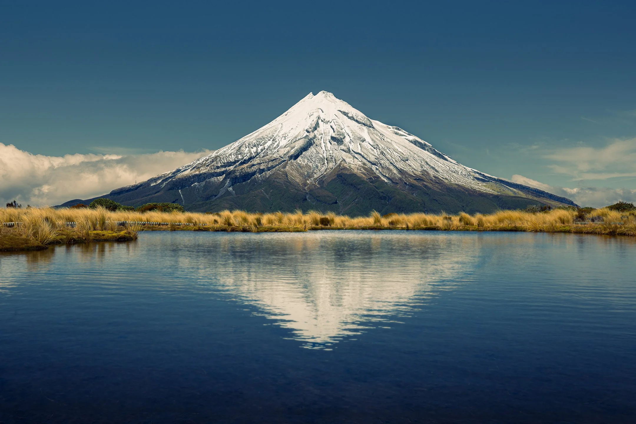 Mount Taranaki reflected in the Pouakai Tarn, its symmetrical volcanic cone doubled in the still alpine water, Egmont National Park, Taranaki, New Zealand.