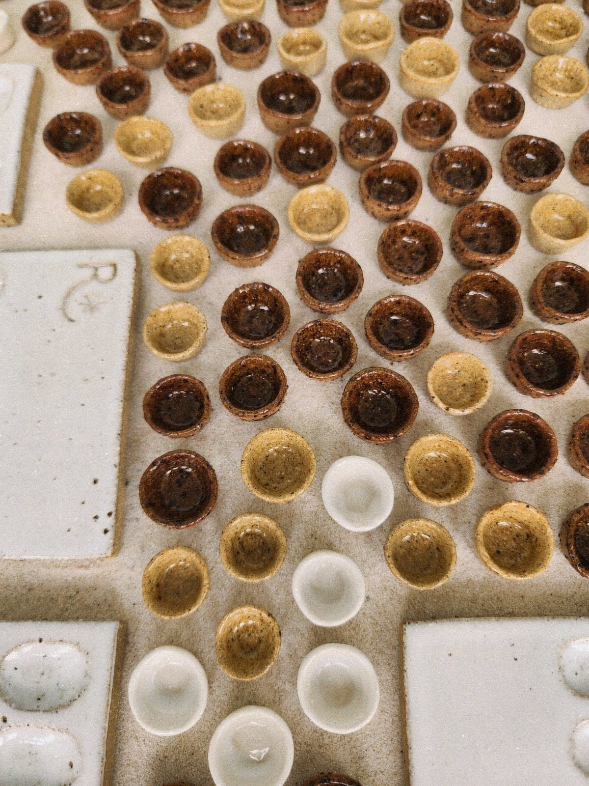 BTS of my little ceramics coming out of their glaze firing 🫶🏻 

5 things I always get asked about this process: 
✨ yes, we make every single palette and each little paint pot from clay in the studio 
🤍 clay is fired twice before it is ceramic once