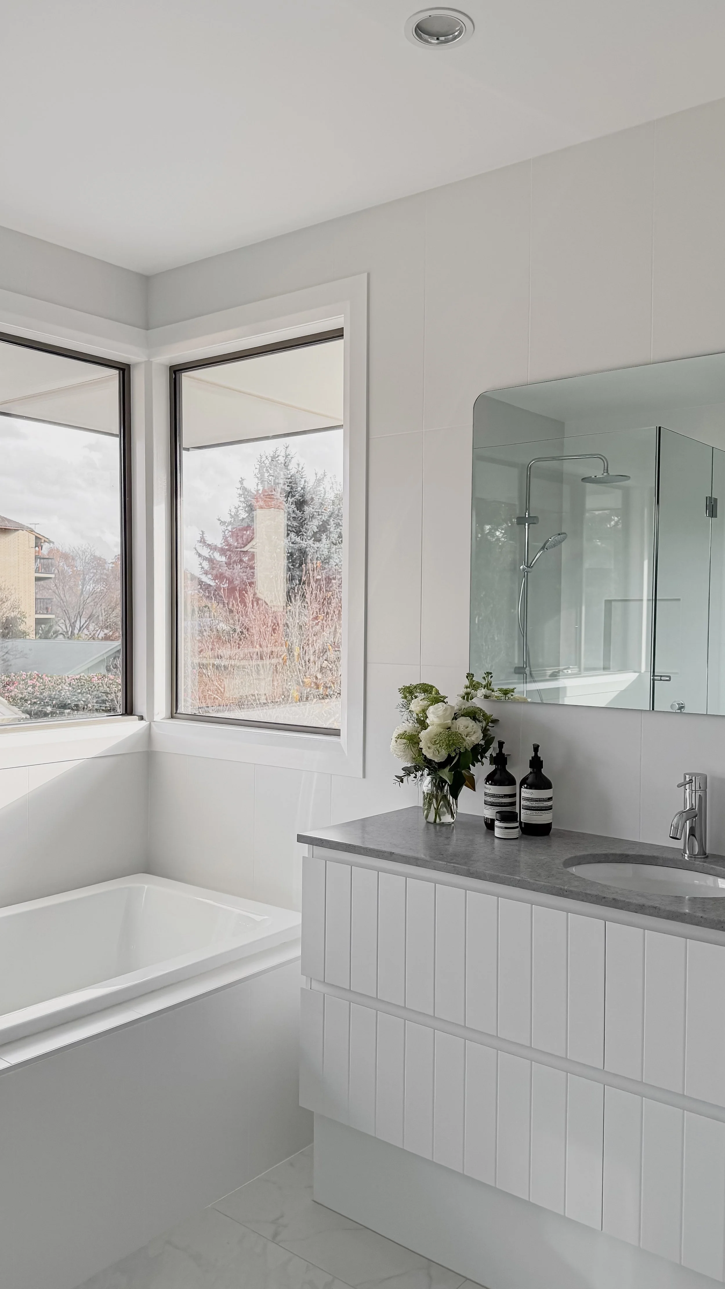 Bathroom with bath and vanity in neutral white tones