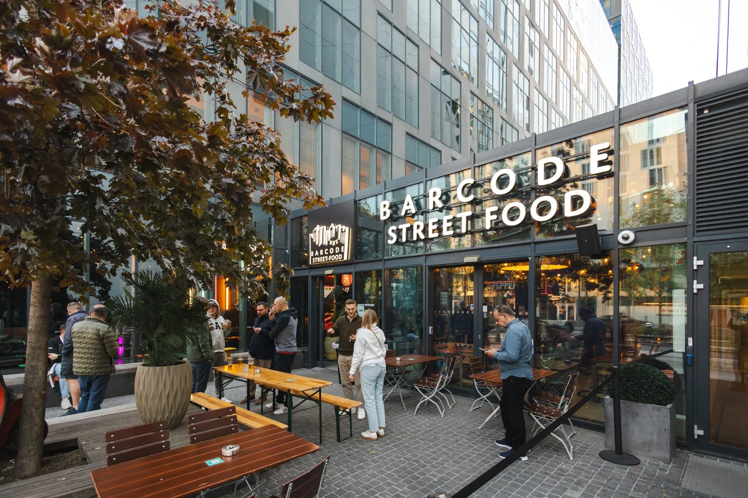 Inngangspartiet til Barcode Street Food i Barcode, Oslo – utendørs sitteplasser og folk som samles rett ved Oslo S