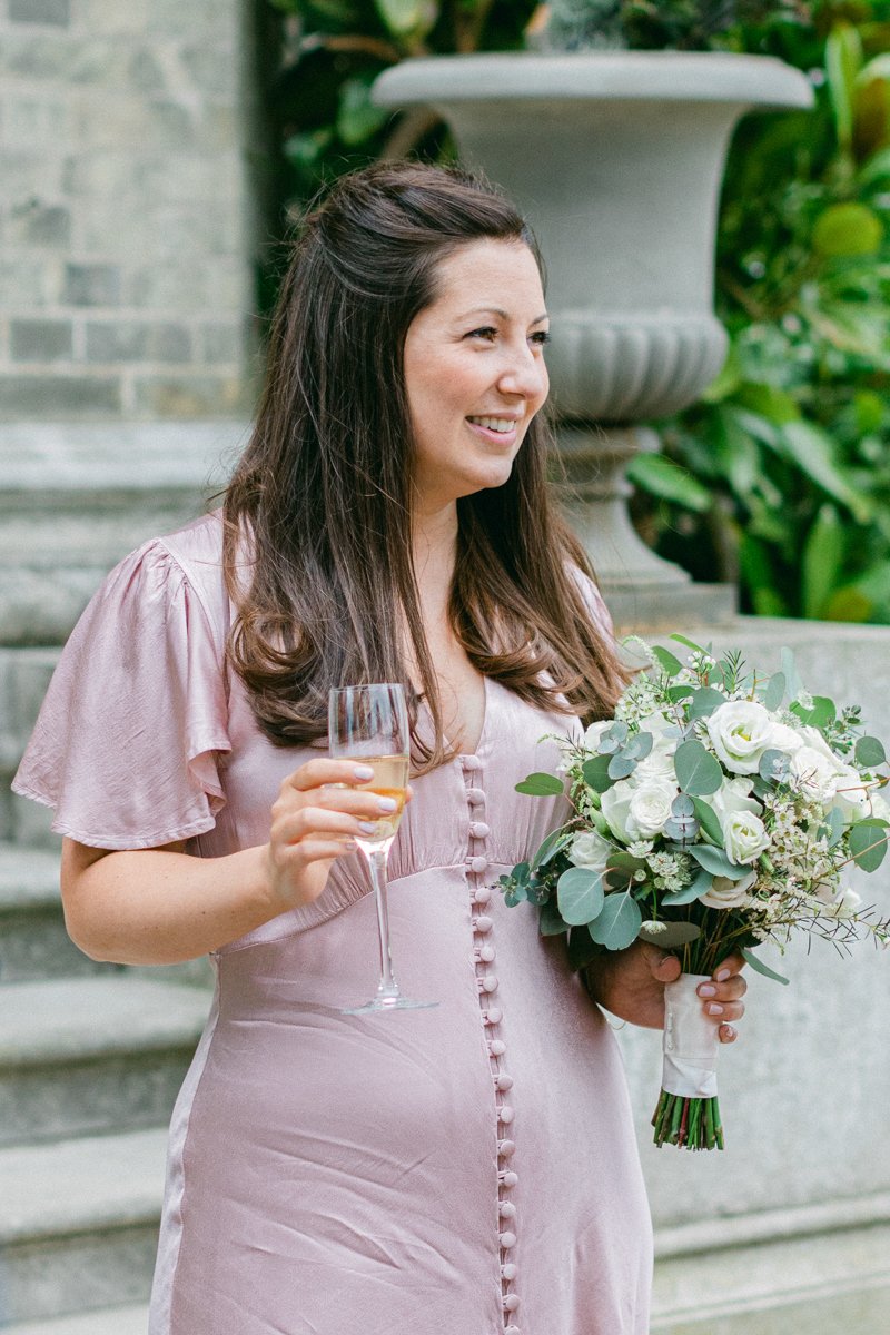 Bridesmaid holding drink and bouquet