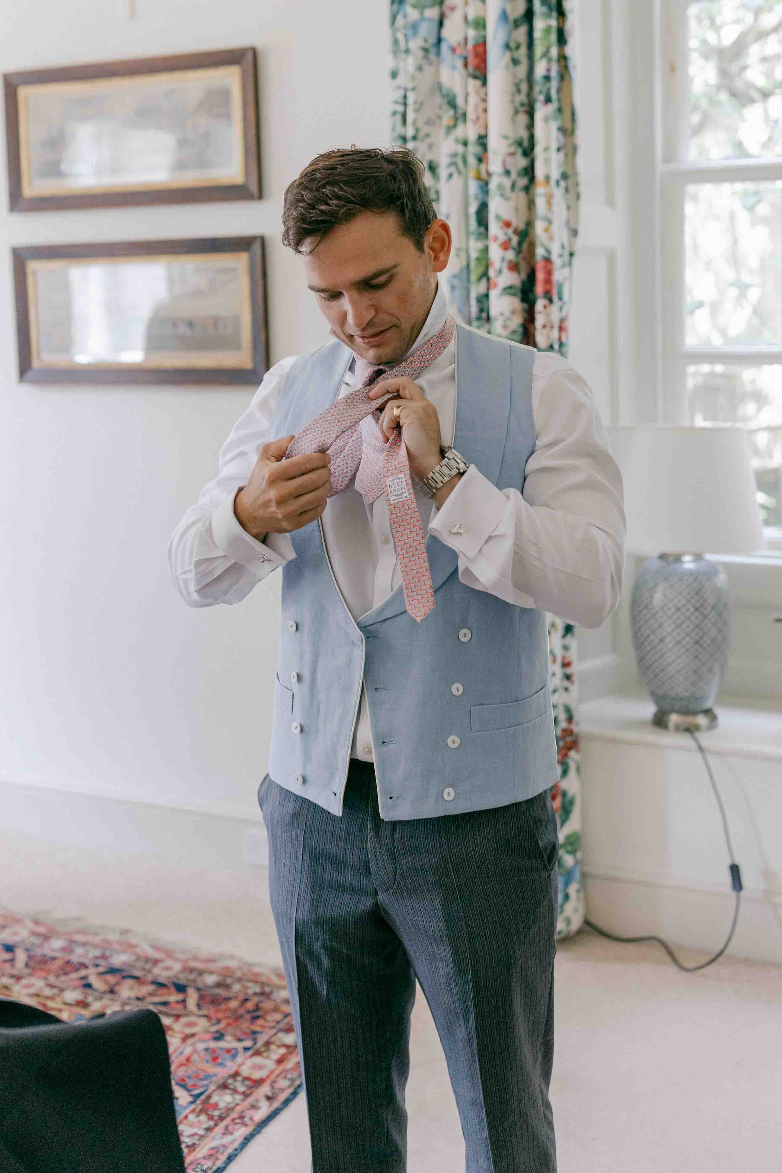  groom putting on tie at Came House 