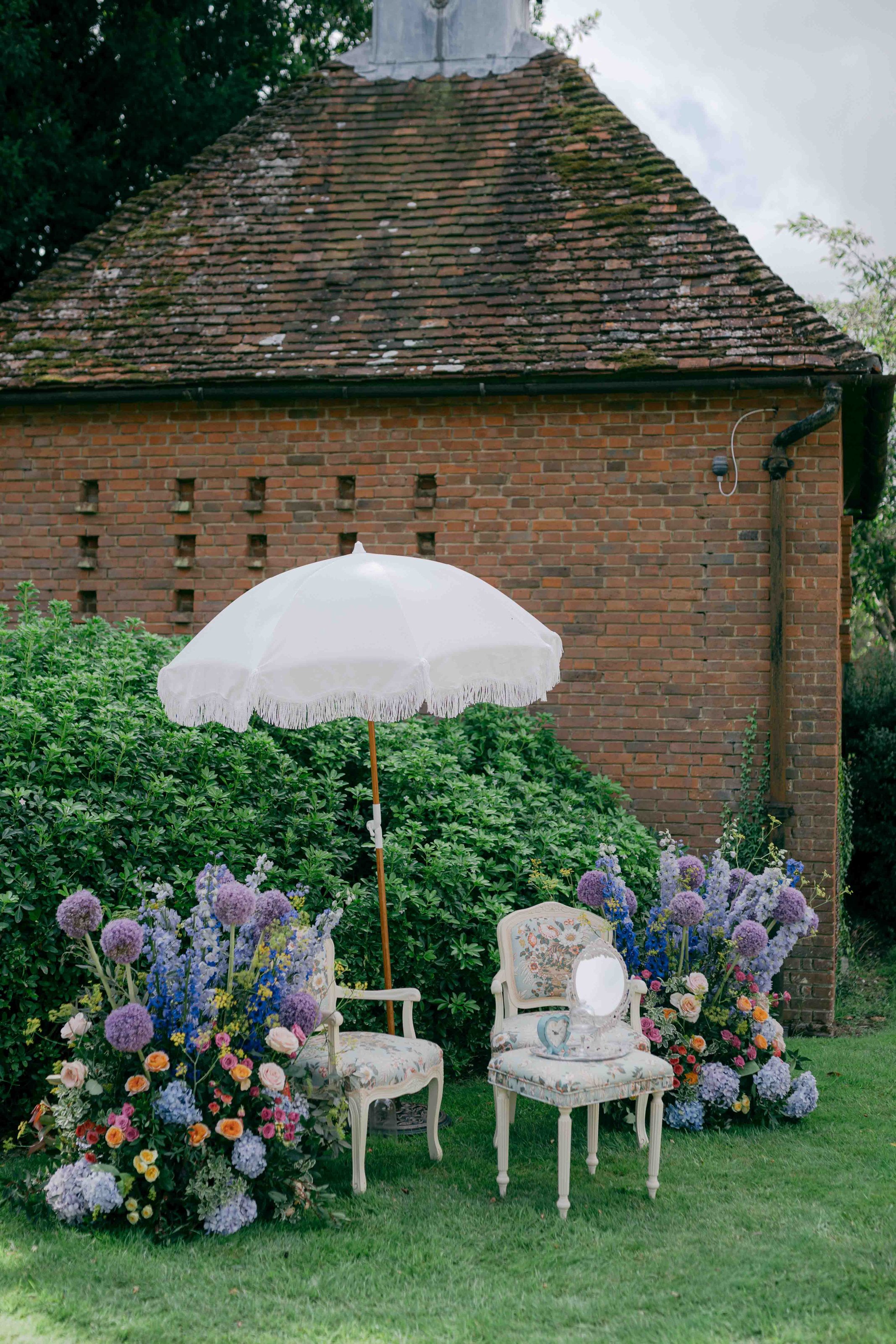  two chairs outside with parasol with florals on either side 