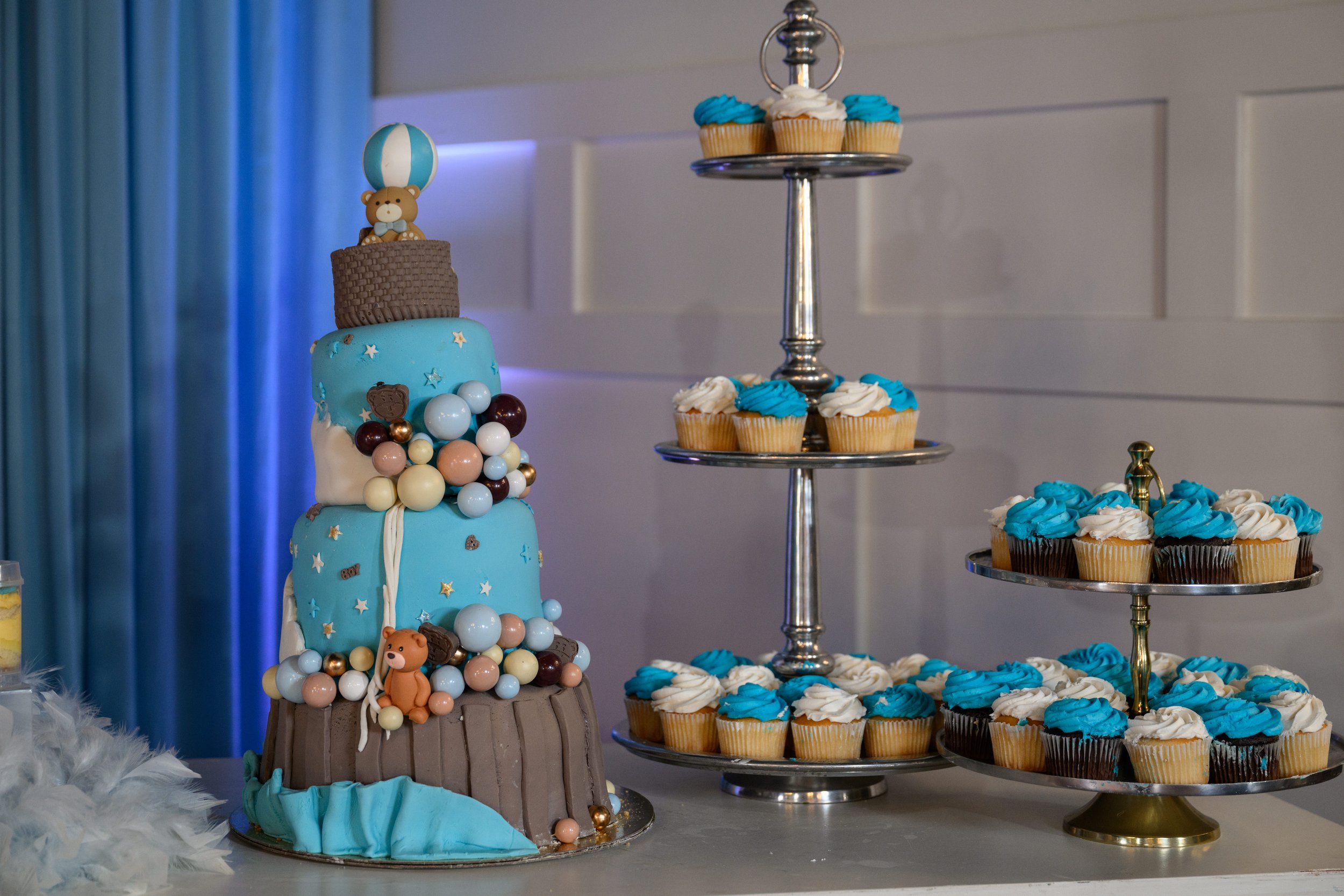 Blue teddy bear themed baby shower cake and cupcake display at an Up, Up and Away celebration in Flowery Branch, Georgia.