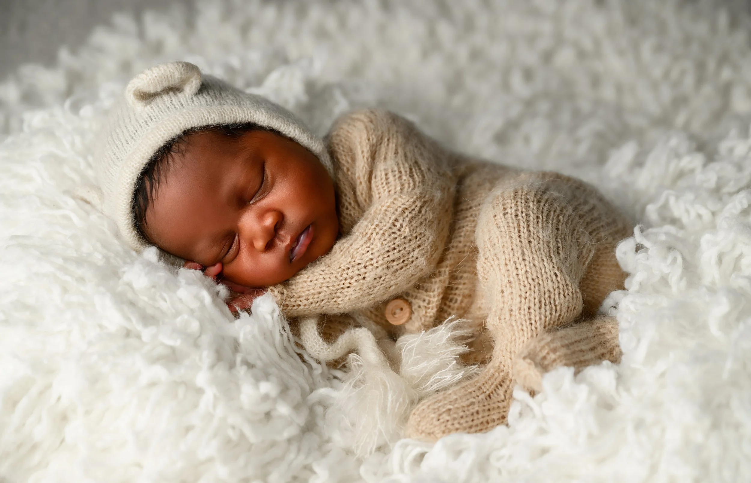 Newborn baby boy sleeping in a neutral knit outfit during an Atlanta newborn photography session.