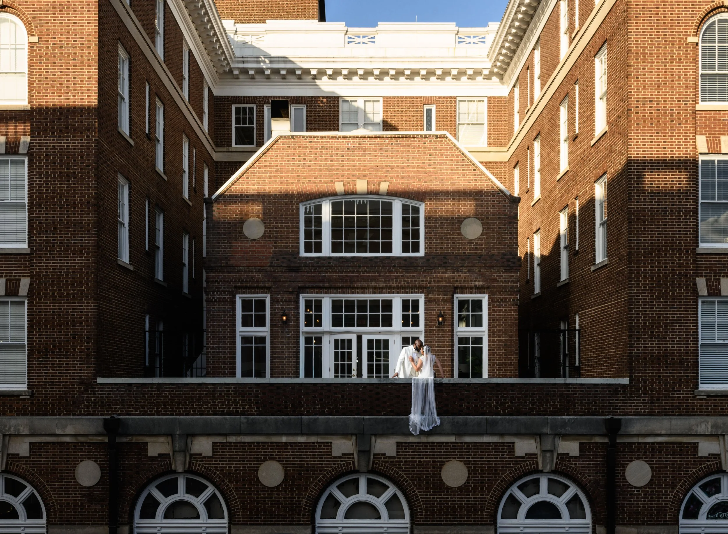 Bride and groom posing on the balcony at Georgian Hall in Atlanta with the bride’s veil draped over the railing.