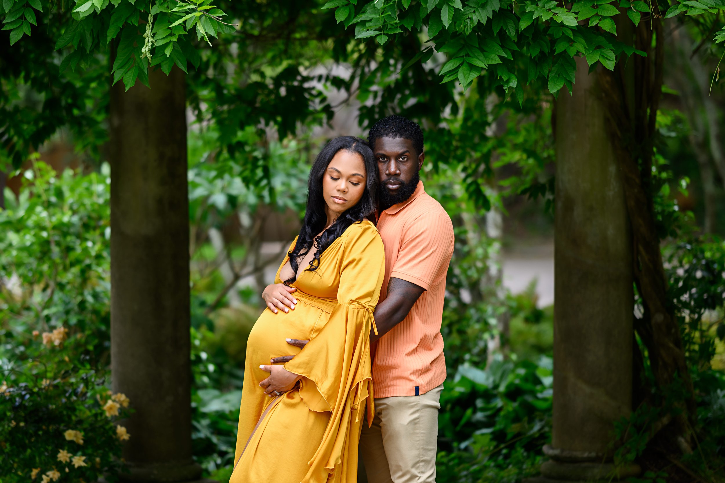 Expectant parents posing together beneath lush greenery during their Atlanta maternity photography session